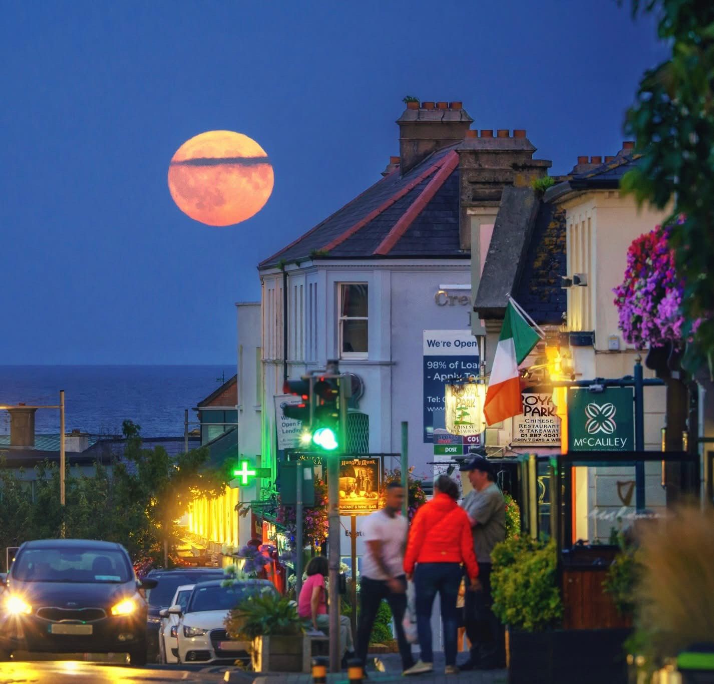 Night street scene with large orange full moon 