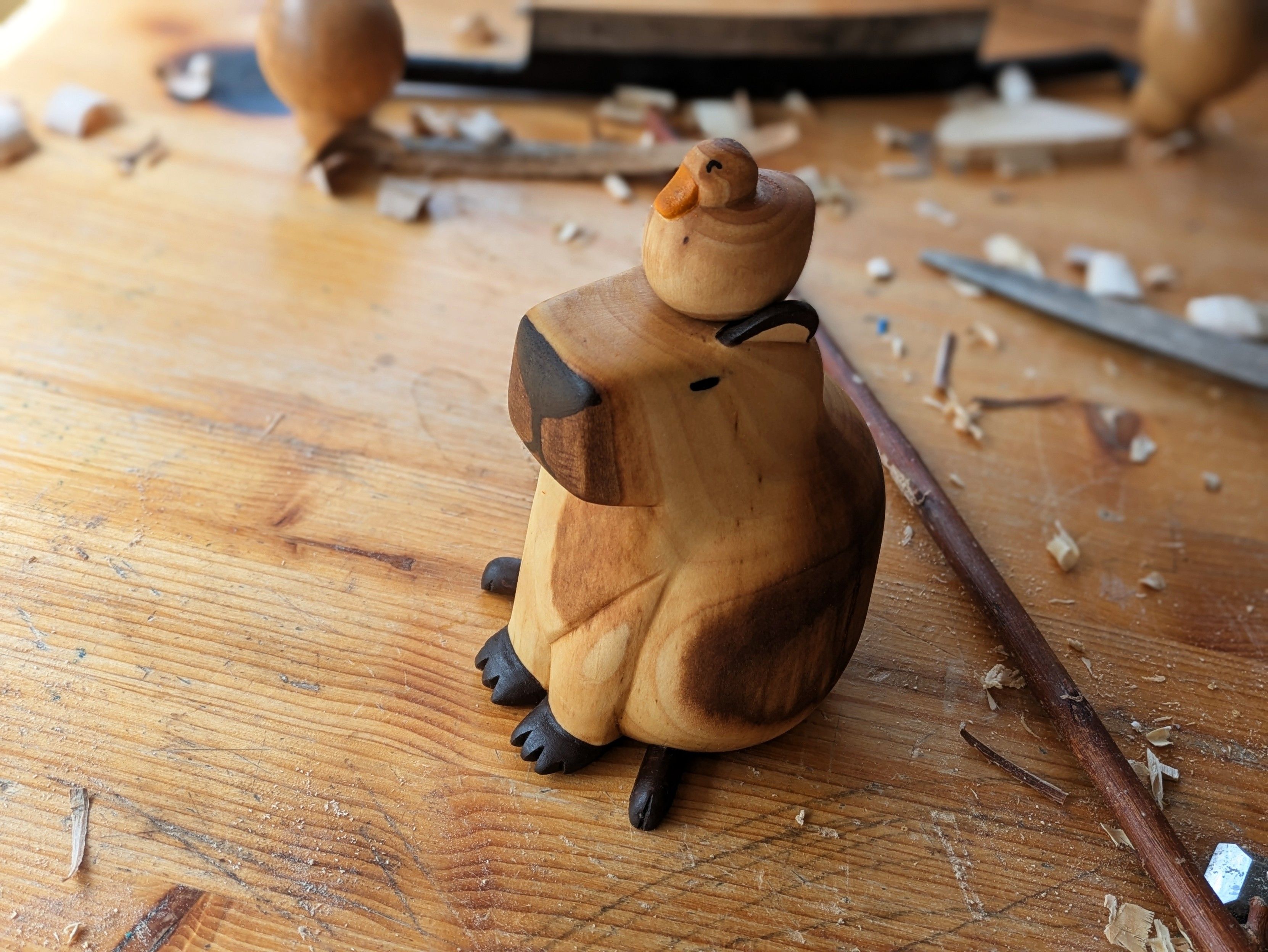 Woodcarved sitting capybara with a duck sleeping on its head