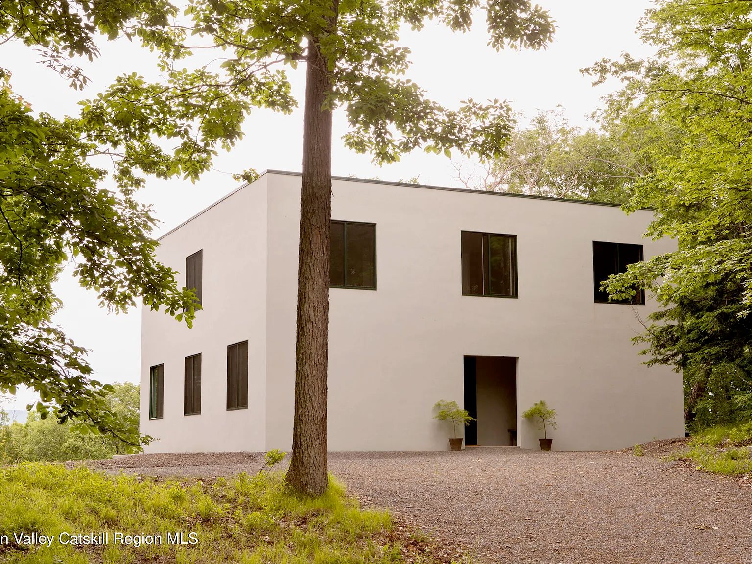 A house that is basically a plain white box with black square windows. There is absolutely no ornamentation and the roof is completely flat. There is no landscaping other than 2 identical small plants on either side of the door. 