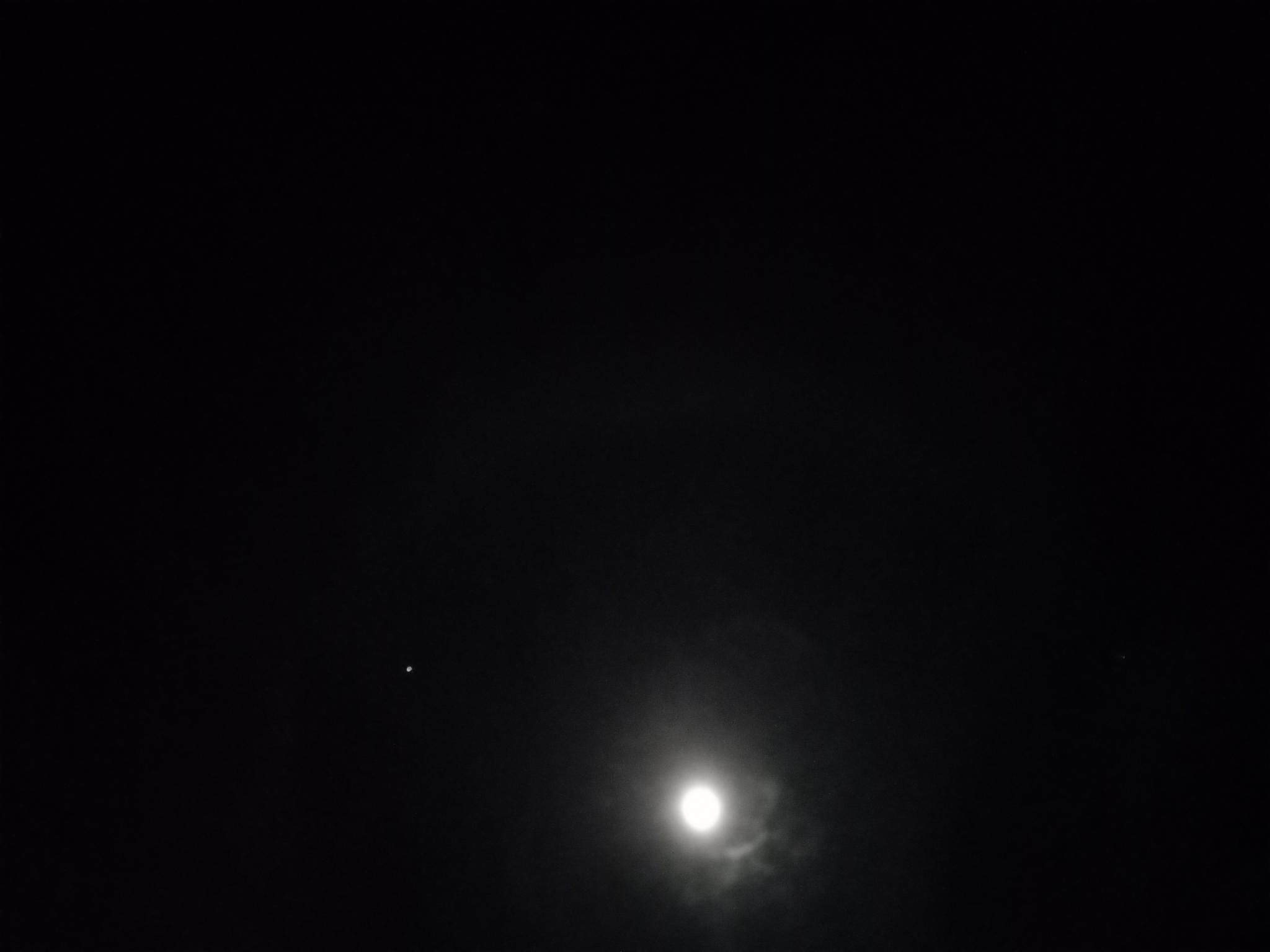 A slightly blurry picture of the full moon with Jupiter nearby, and a very faint moonbow above