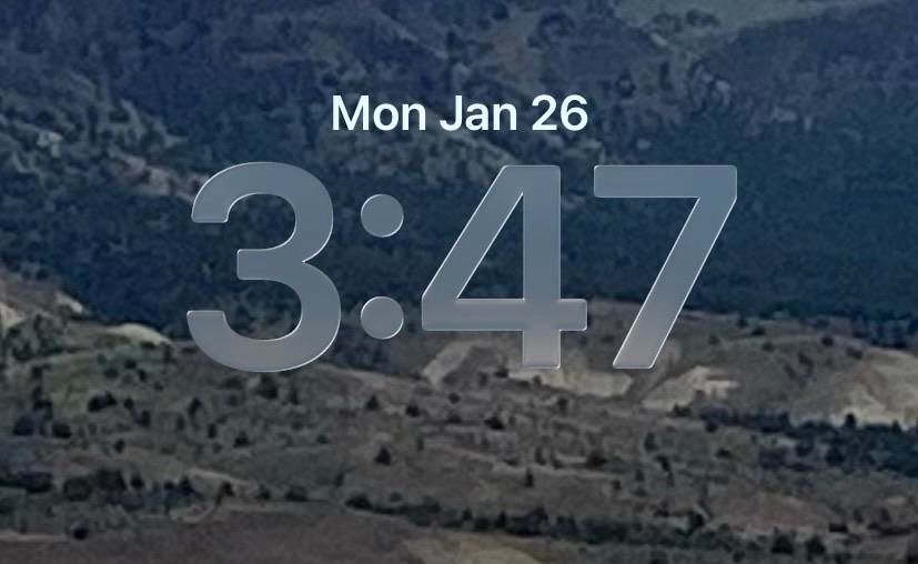 My iPhone lock screen. 
Mon Jan 26
3:47
The date is solid white. The time is transparent, and the tail of the 4 is disappearing into the background. 
