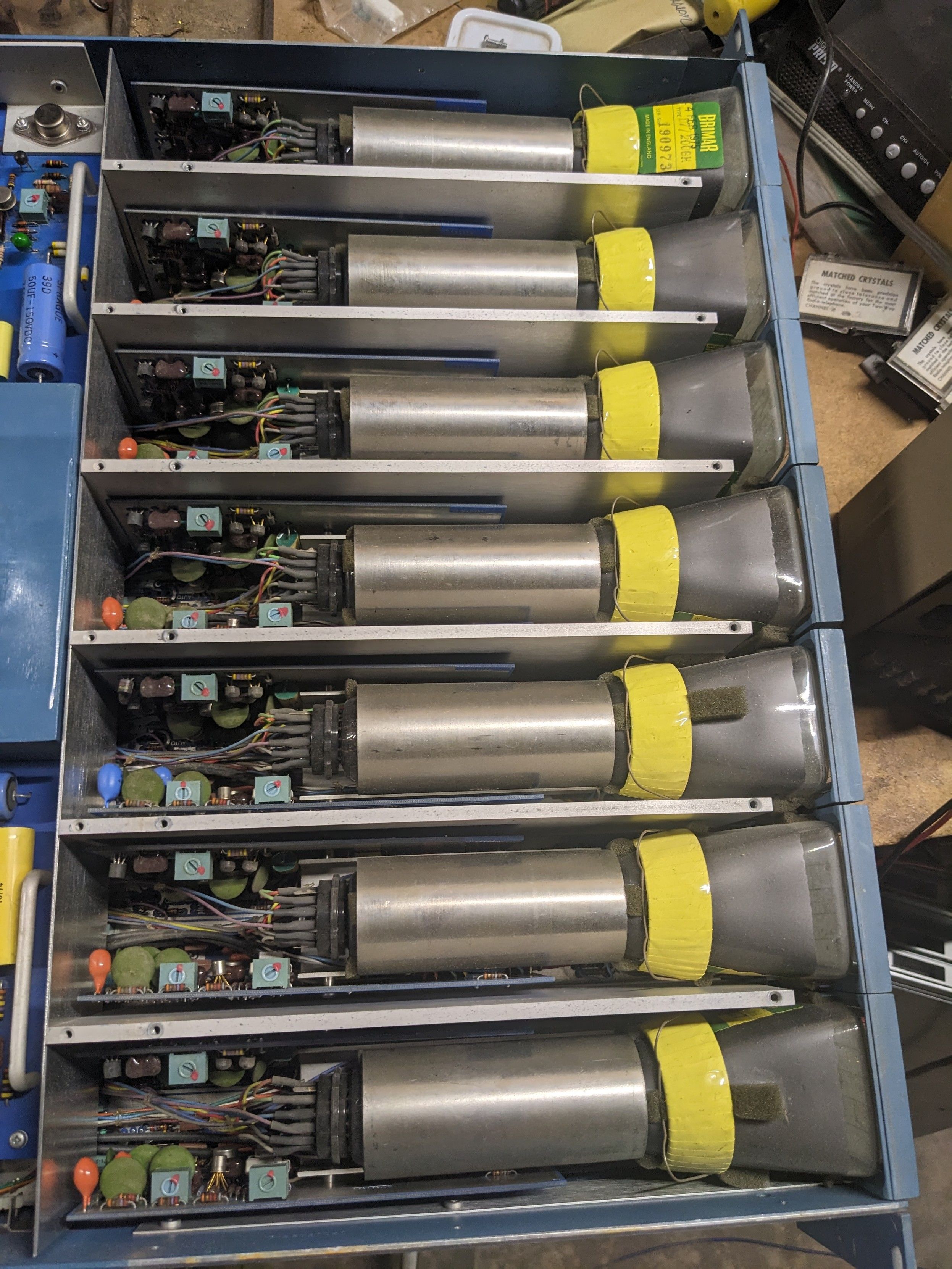 7 crt's in a row shown from above, each with 2 pcbs, presumably horizontal and vertical drive circuits.  Each cry has a coil if wite wrapped in bright yellow tape like a space-age necklace and an aluminum pipe along the neck, presumably for shielding from the 6 others