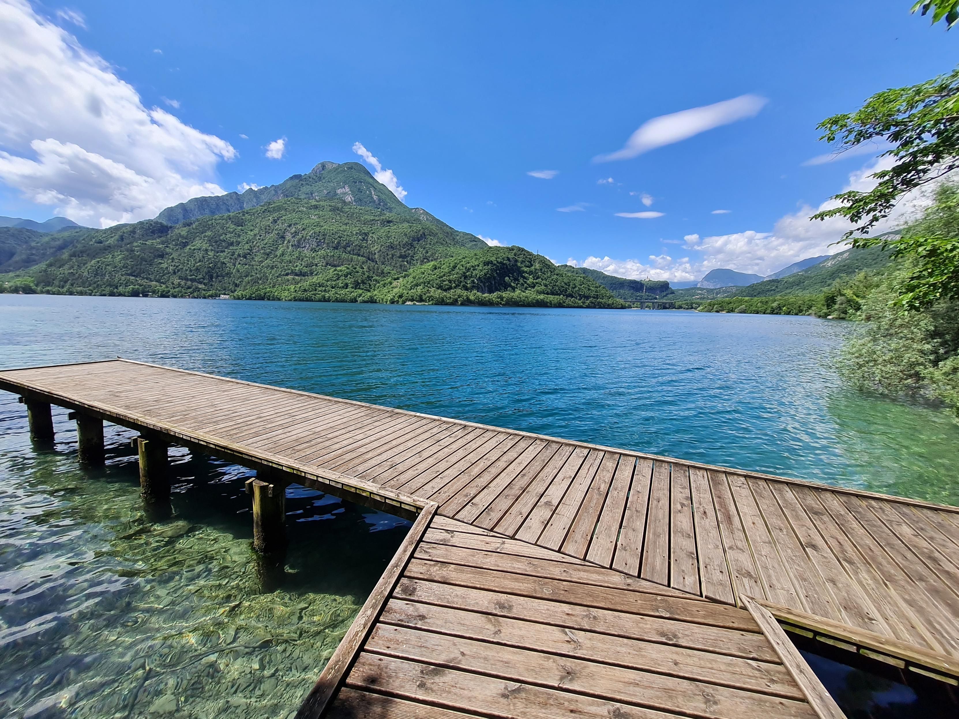 Pontile presso il lago si Cavazzo. Sullo sfondo, momtagne e cielo azzurro.
