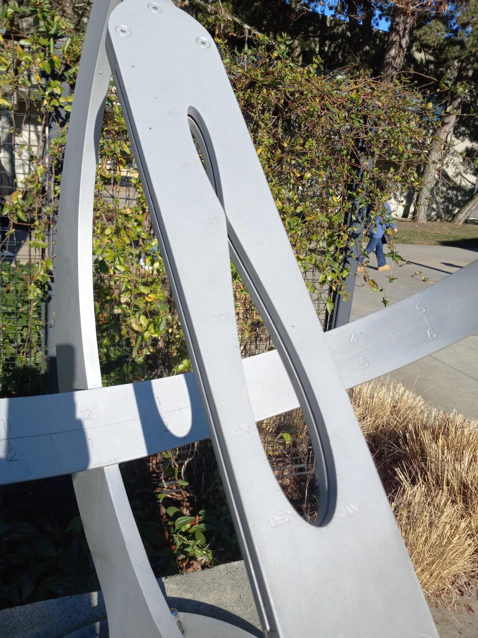 A sundial that incorporates an analemma for more accuracy in timing.  The sun is shining through the analemma making a sun-shadow line that perfectly tells the time when projected onto a curved metal piece with timestamps on it.