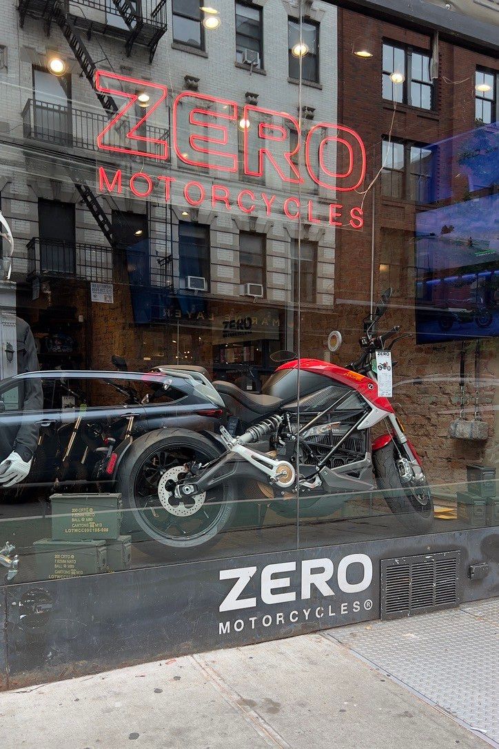 A storefront with a sign, “ZERO motorcycles”. But the window contains one motorcycle.