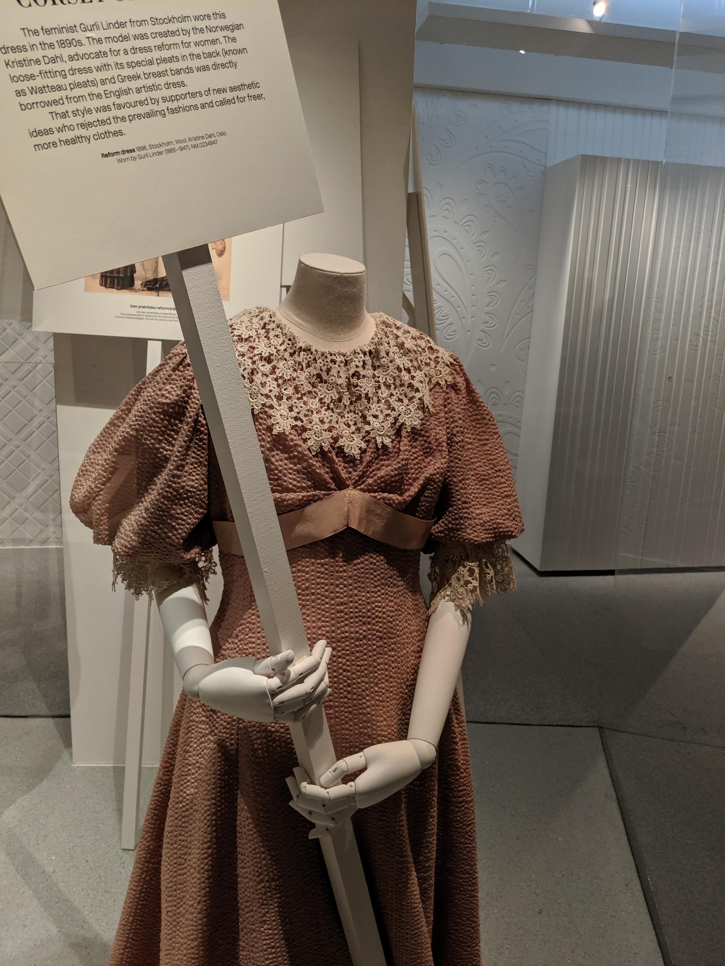 Reform or rational dress exhibit at a museum. The dress has no corset and looks comfy. The mannequin is holding a protest sign. 