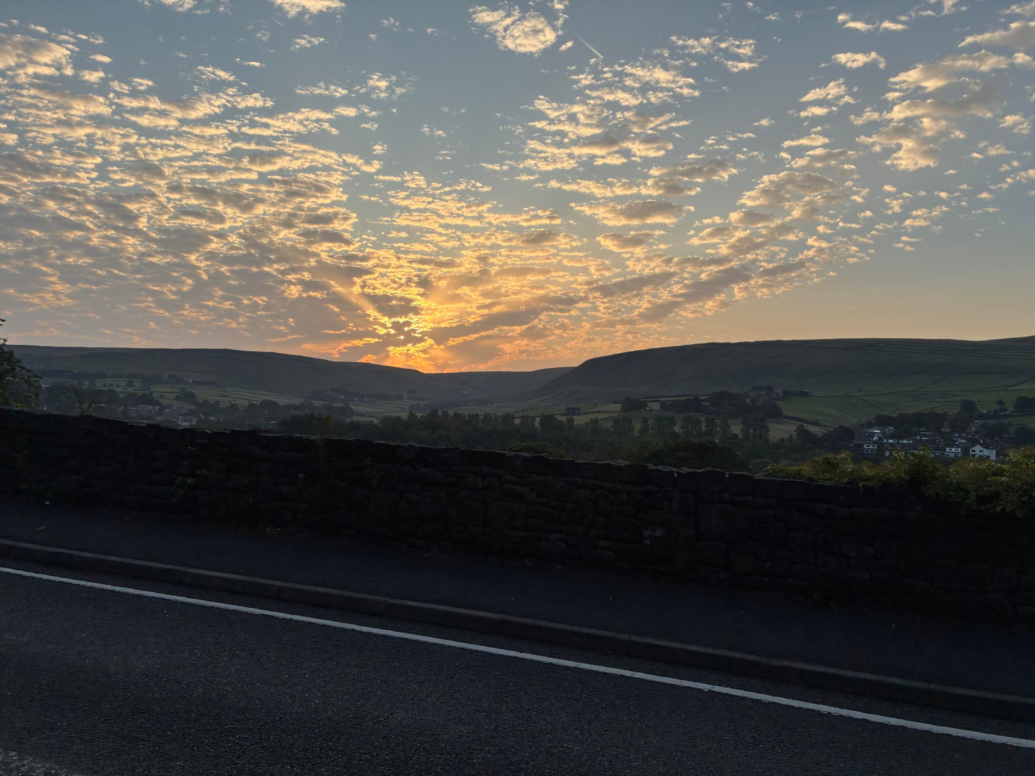 A scenic landscape at sunrise, showcasing a vibrant sky filled with clouds and warm colors.