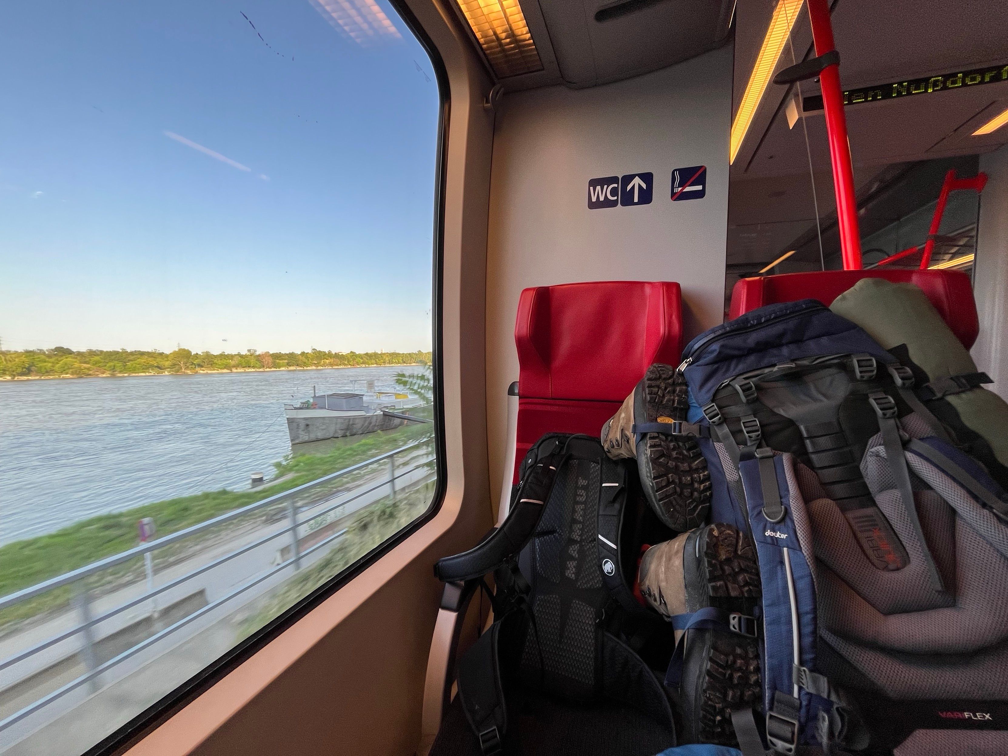 Picture in a train with a big backbag, to the left the view out a window with a river visible