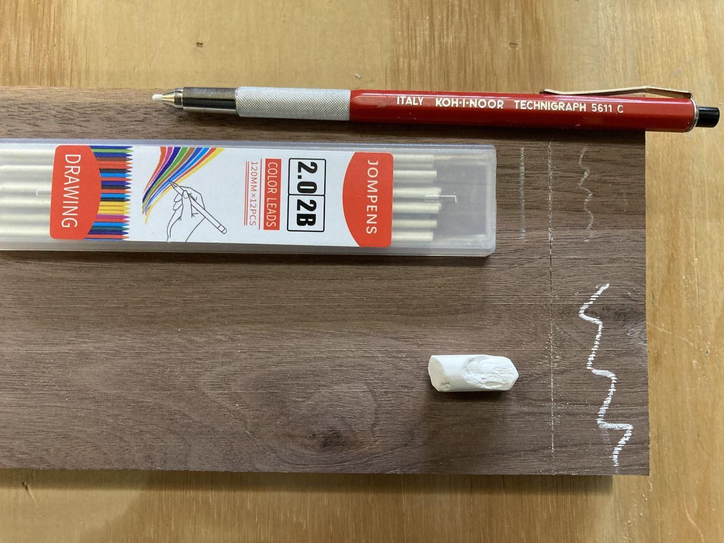 Image showing how white drawing lead looks compared to chalk on a piece of dark walnut wood.  