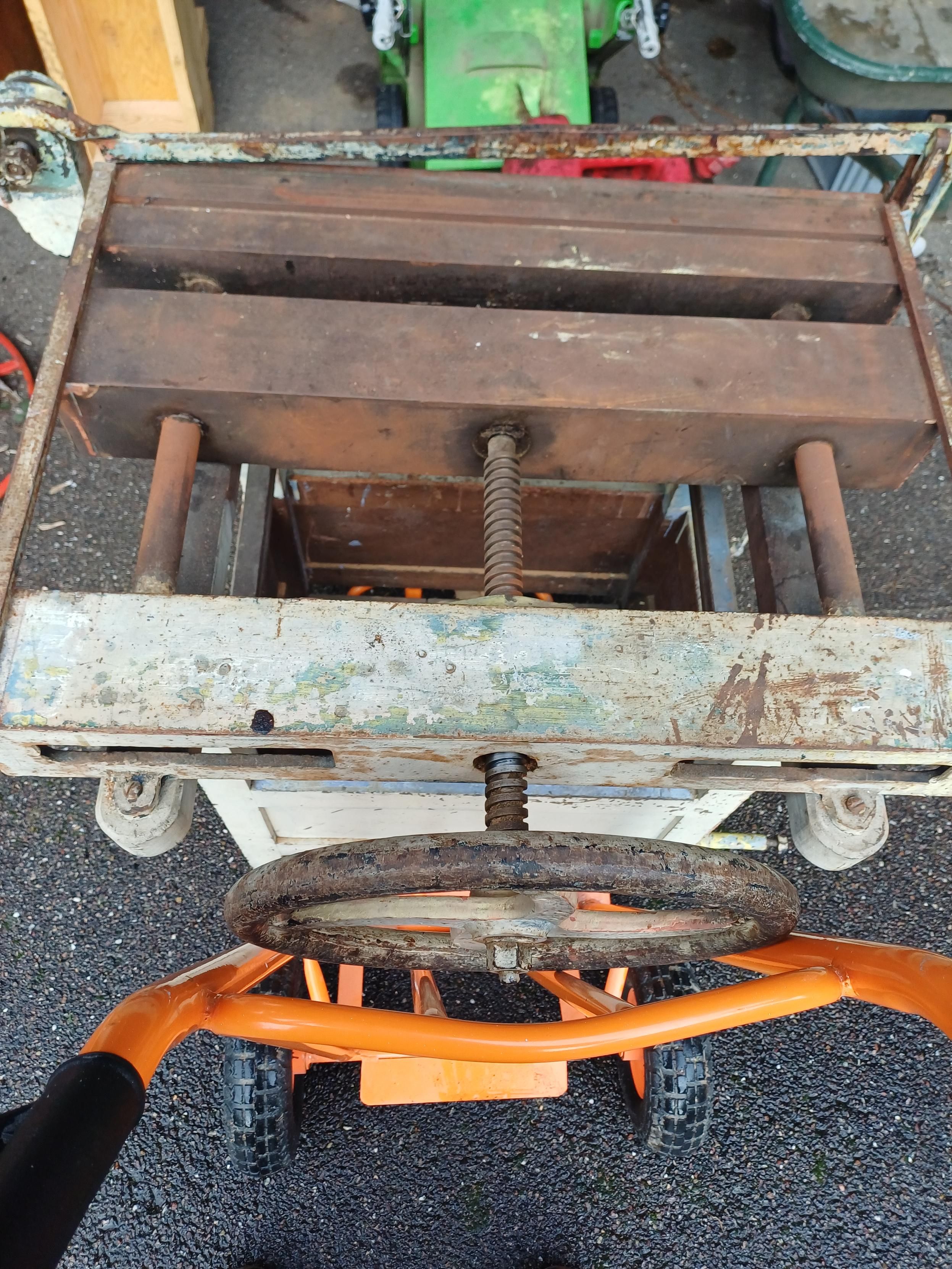 Photo
Combiné à reliure, sur un diable orange.
La partie supérieure est en fonte rouillée avec une manivelle en fonte et une vis pour la partie mobile. Le piètement est en bois peint en gris-vert.