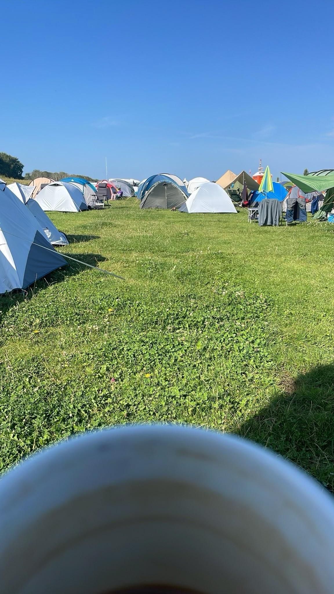 Green grass, lots of tents. Coffee cup. 