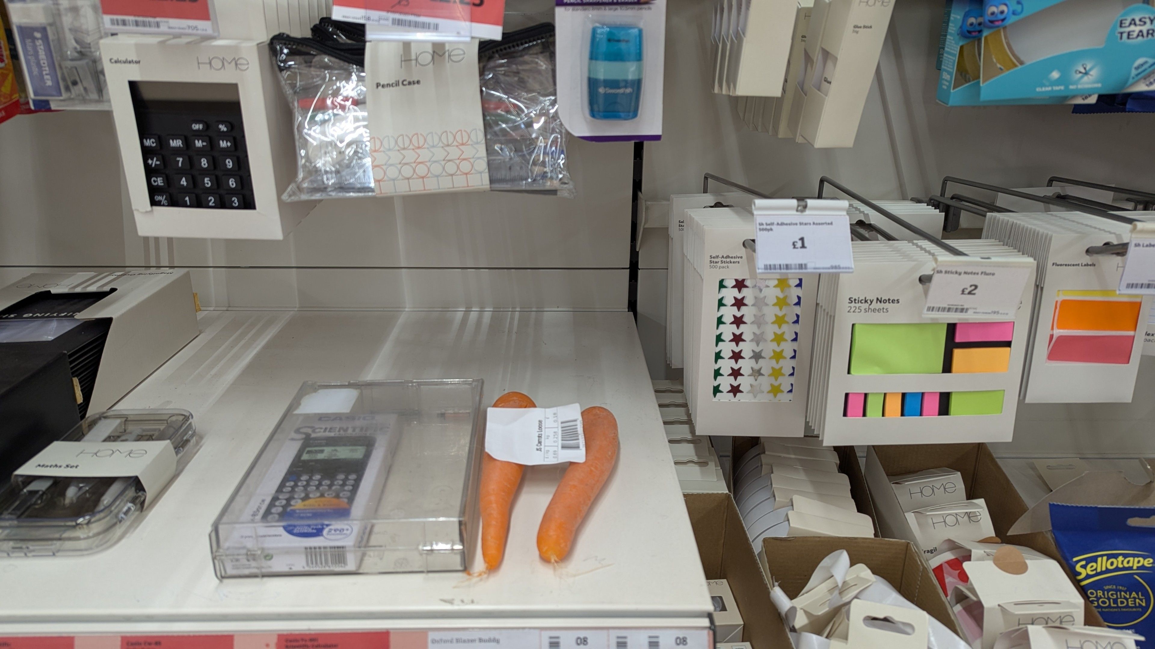 The picture shows a couple of carrots in the stationery area of a supermarket, perhaps someone didn't want them and just randomly put them there. 

This amused me so I took this picture