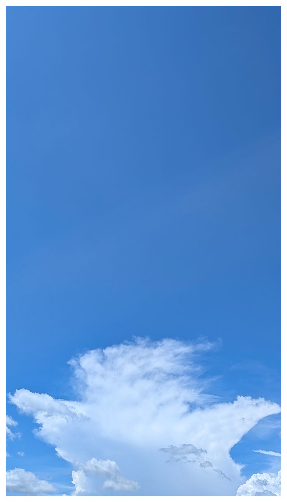 a large loud appears to be a person with arms outstreched in a "ta-da!" gesture. The background is clear blue sky.