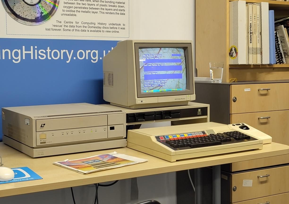 Photo of a slightly swollen BBC Micro with a gigantic laserdisc player to the left and a weird trackball controller to the right. The person demonstrating it was one of the schoolchildren who supplied photos and descriptions of their community, with zero fact checking by the BBC...