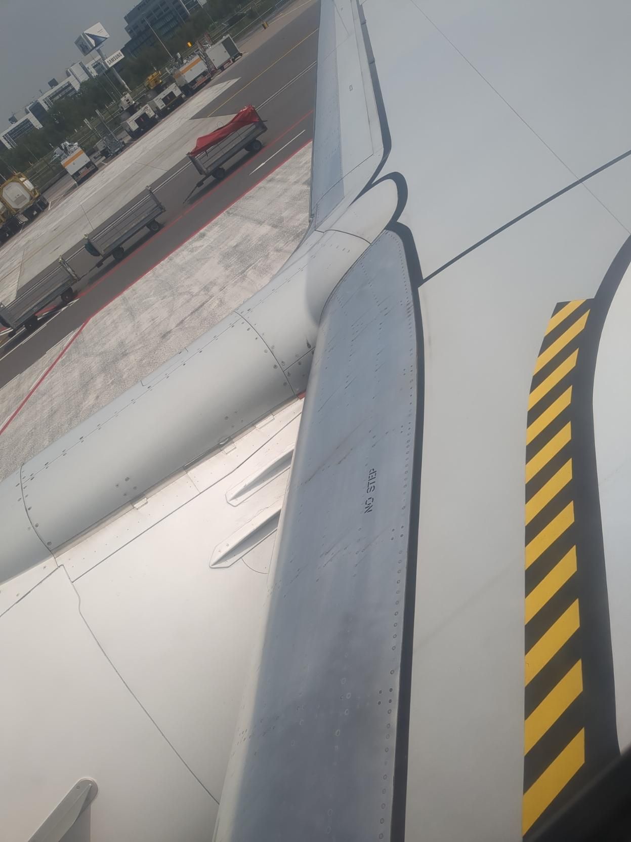 view out of a window of a boeing 737, seat 13F - just above the right window. I try to avoid flying in general, or, failing that, stick to the "if it's boeing, I'm not going" policy, but it is what it is. in the space between the engine nacelle and main fuselage, the leading edge of the wing is metallic, with "NO STEP" stencilled onto the metallic surface.