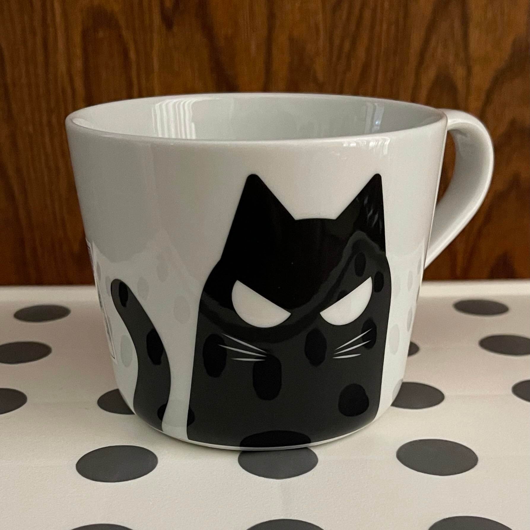 Photo of a white mug with fierce cartoon black cat on it 