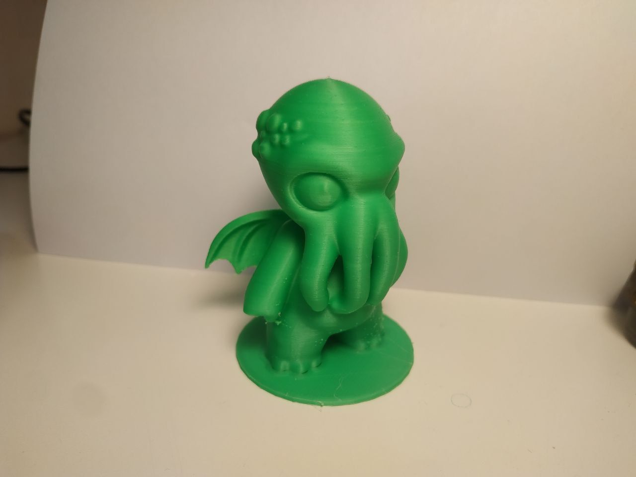 Una stampa 3d di un piccolo e puccioso Cthulhu di colore verde sui sfondo bianco.