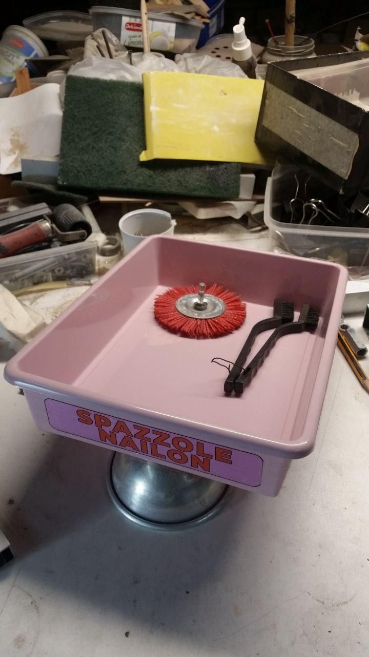 Vaschetta in plastica rosa con etichetta (rosa) "spazzole nailon".
Dentro una spazzola rosso aranciato da montare su un mandrino e due spazzoline nere a mano (non sono spazzoloini da denti).