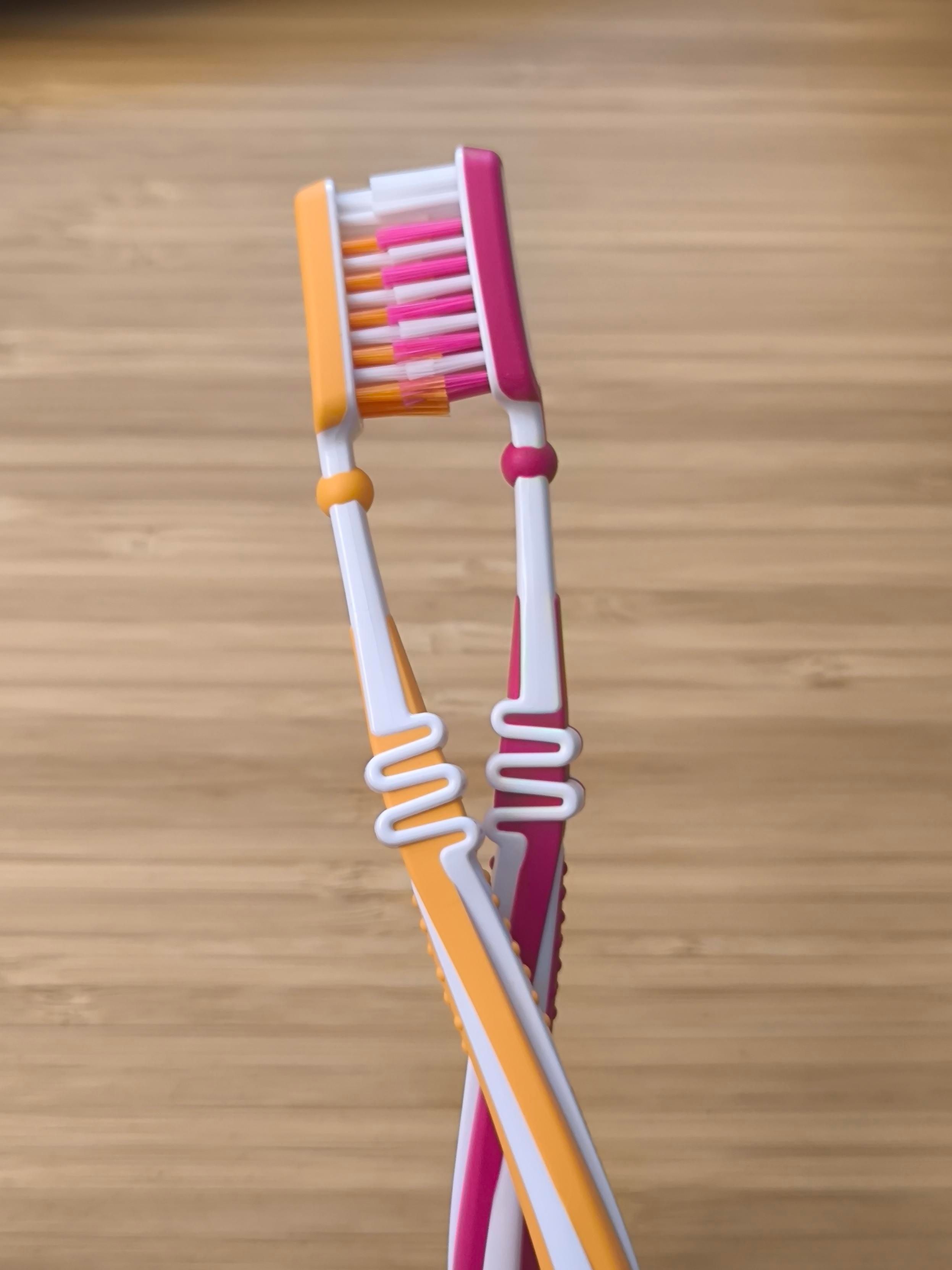 a magenta-white and orange-white toothbrush with their bristles pushed into each other, looking like they're kissing. (the colors are reminiscent of the lesbian pride flag)
