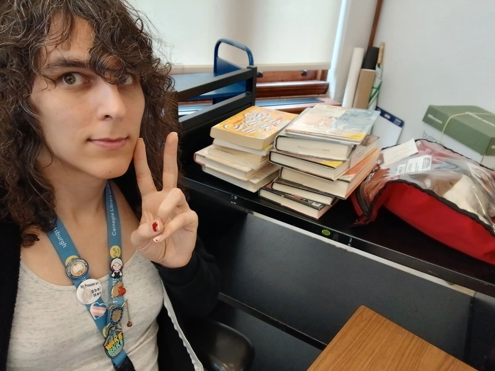 bea sitting in front of a library cart stacked with books