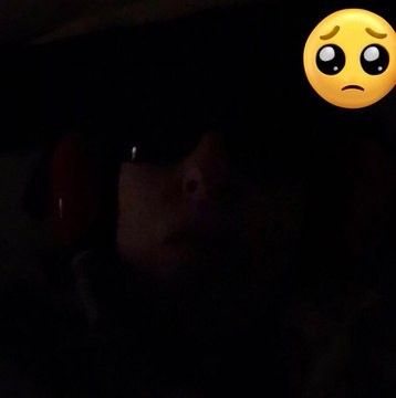 Sick woman in bed in dark with ear defenders on to block sensory overload 