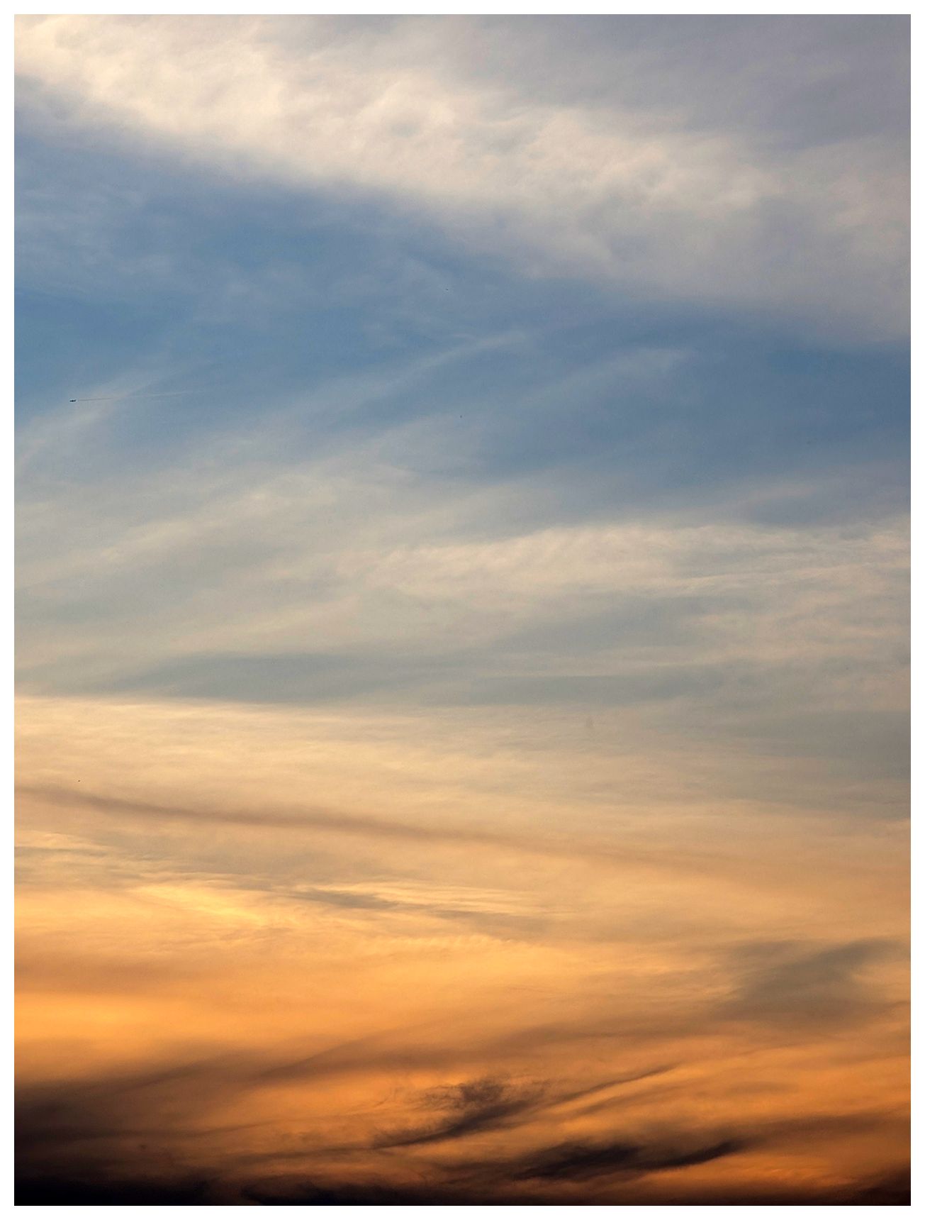 ai-assistedd alt text:

Soft, wispy clouds fill the sky at sunset. The lower part glows with warm orange and golden hues while the upper sky shifts to pale blue and soft gray, creating a tranquil gradient. The clouds appear gently streaked across the sky.