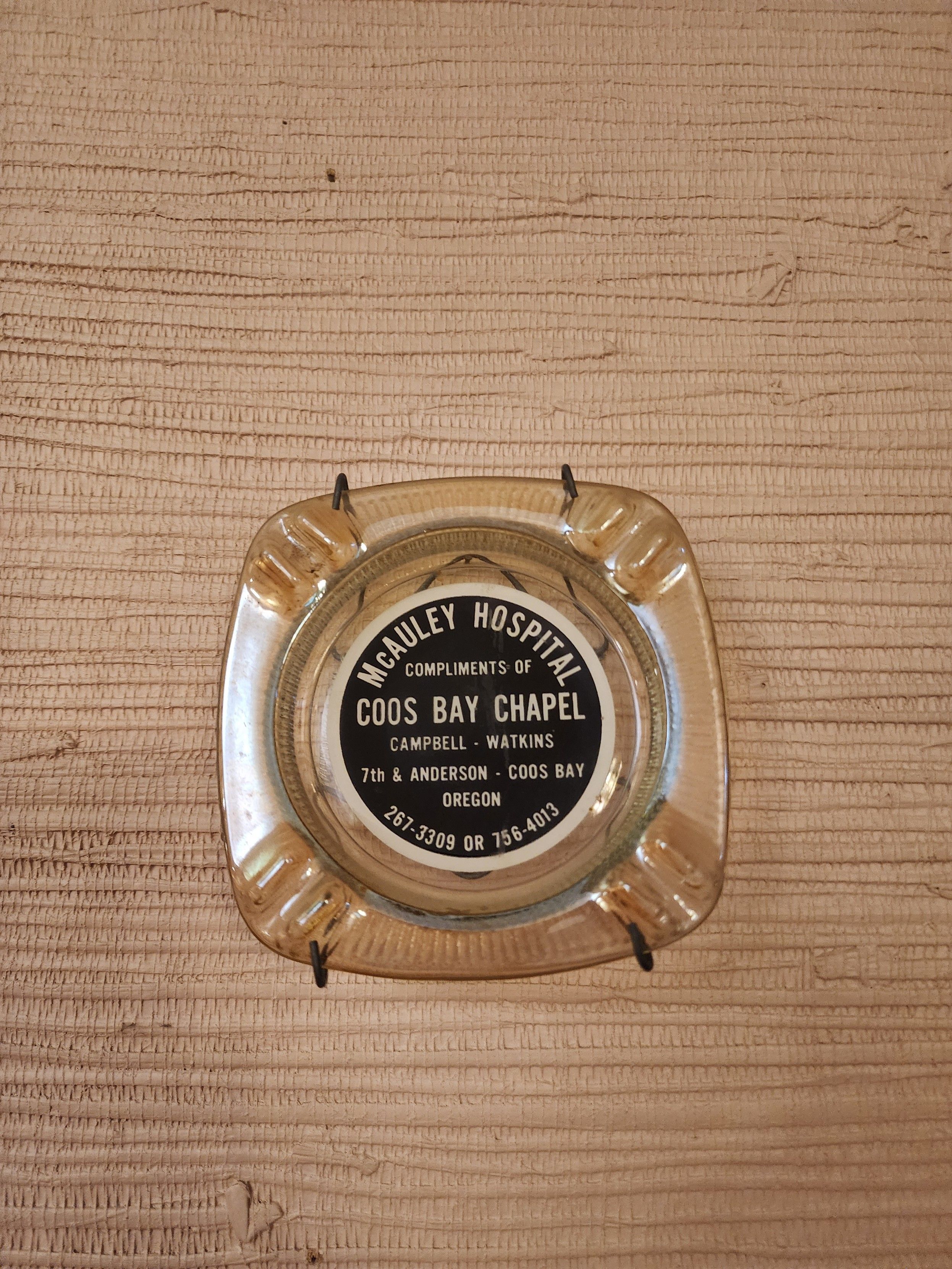 A glass ashtray with a hospital logo, courtesy of a funeral home 
