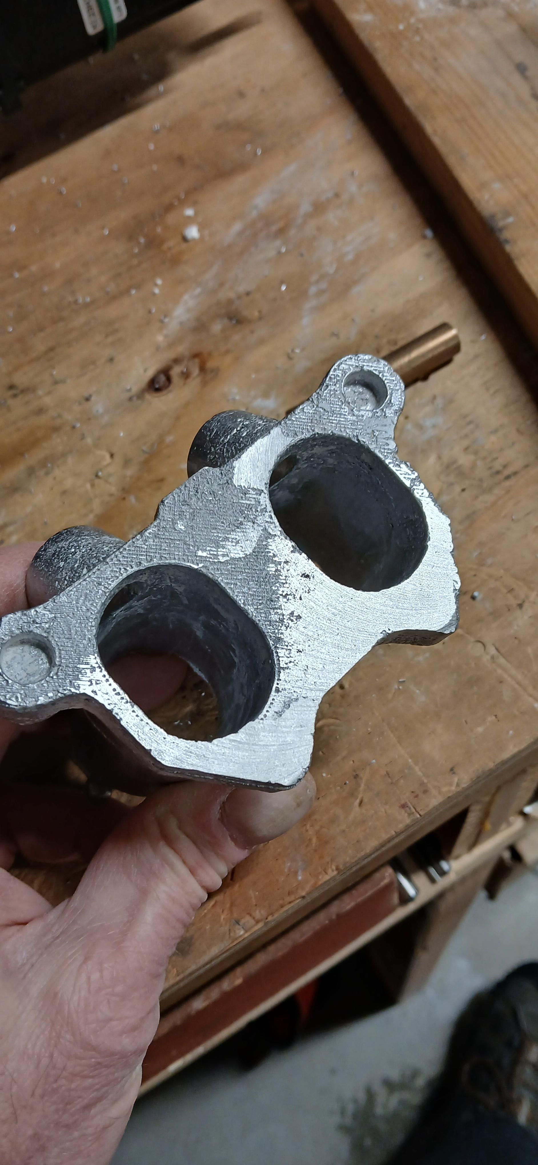 Aluminum intake manifold casting with lower half fly cut and shiny upper half still showing the 3d print texture.