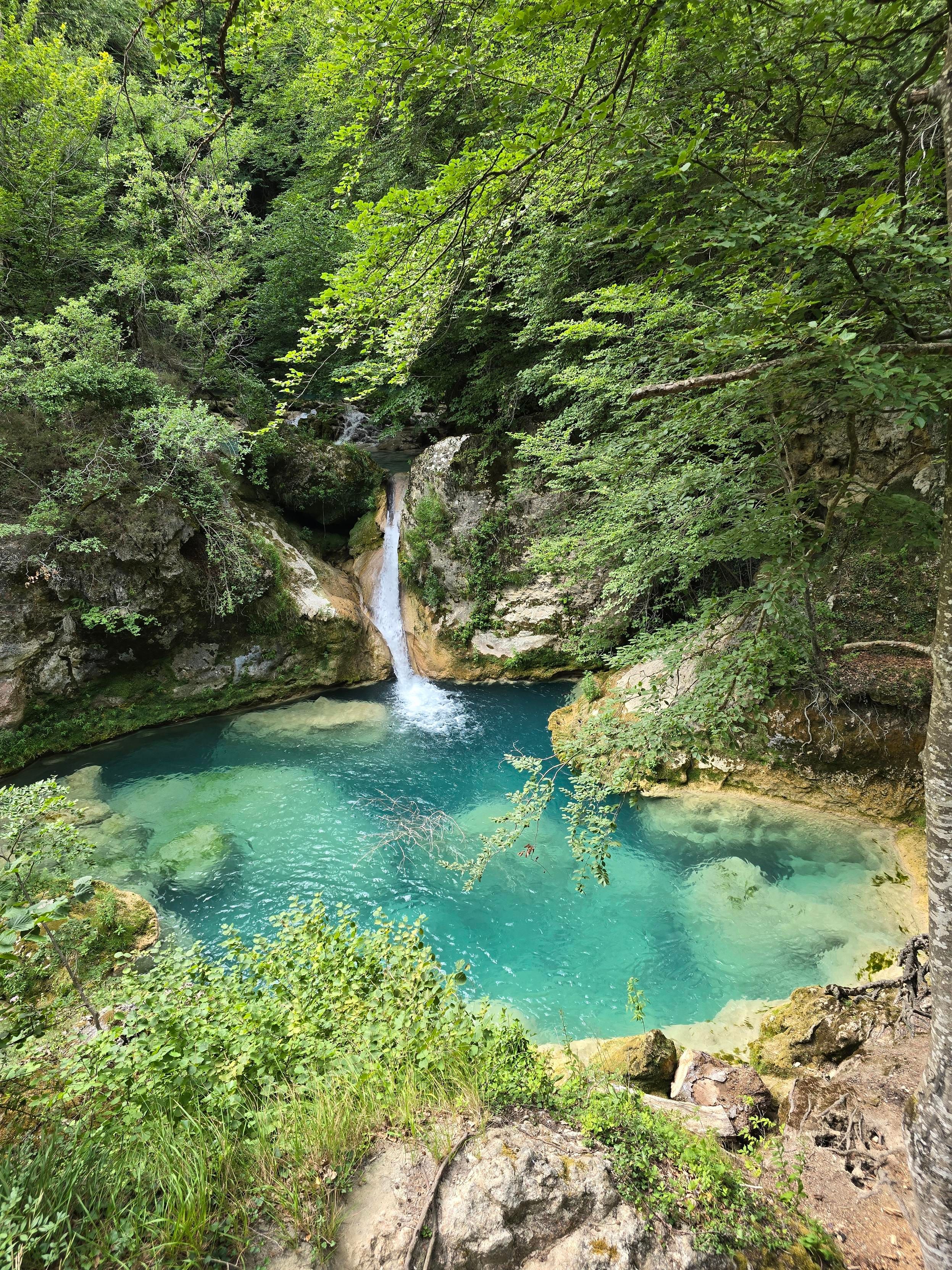 Nacedero del río Urederra en Navarre : vue sur une cascade se jetant dans des eaux bleu turquoise d'un petit lac.