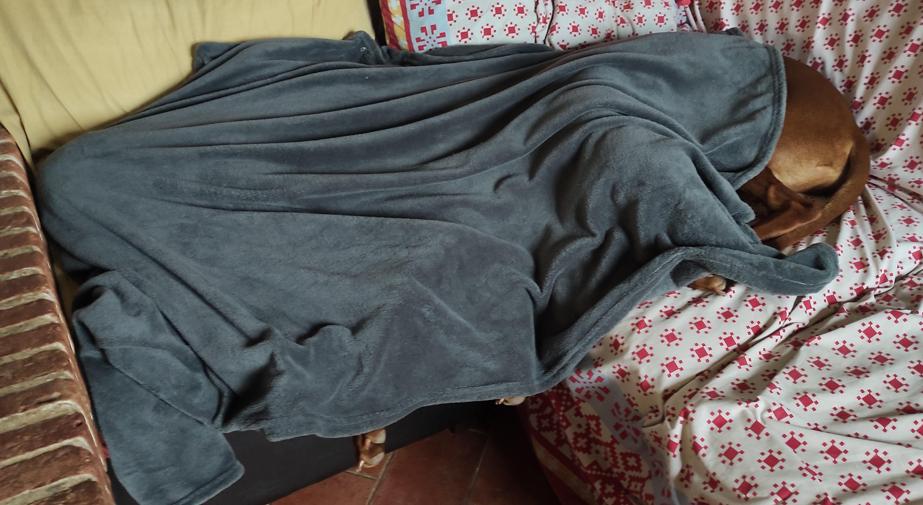 le due bionde accoccolate sul divano sotto una coperta grigia di pile, telo sul divano bianco con fantasia geometrica rossa