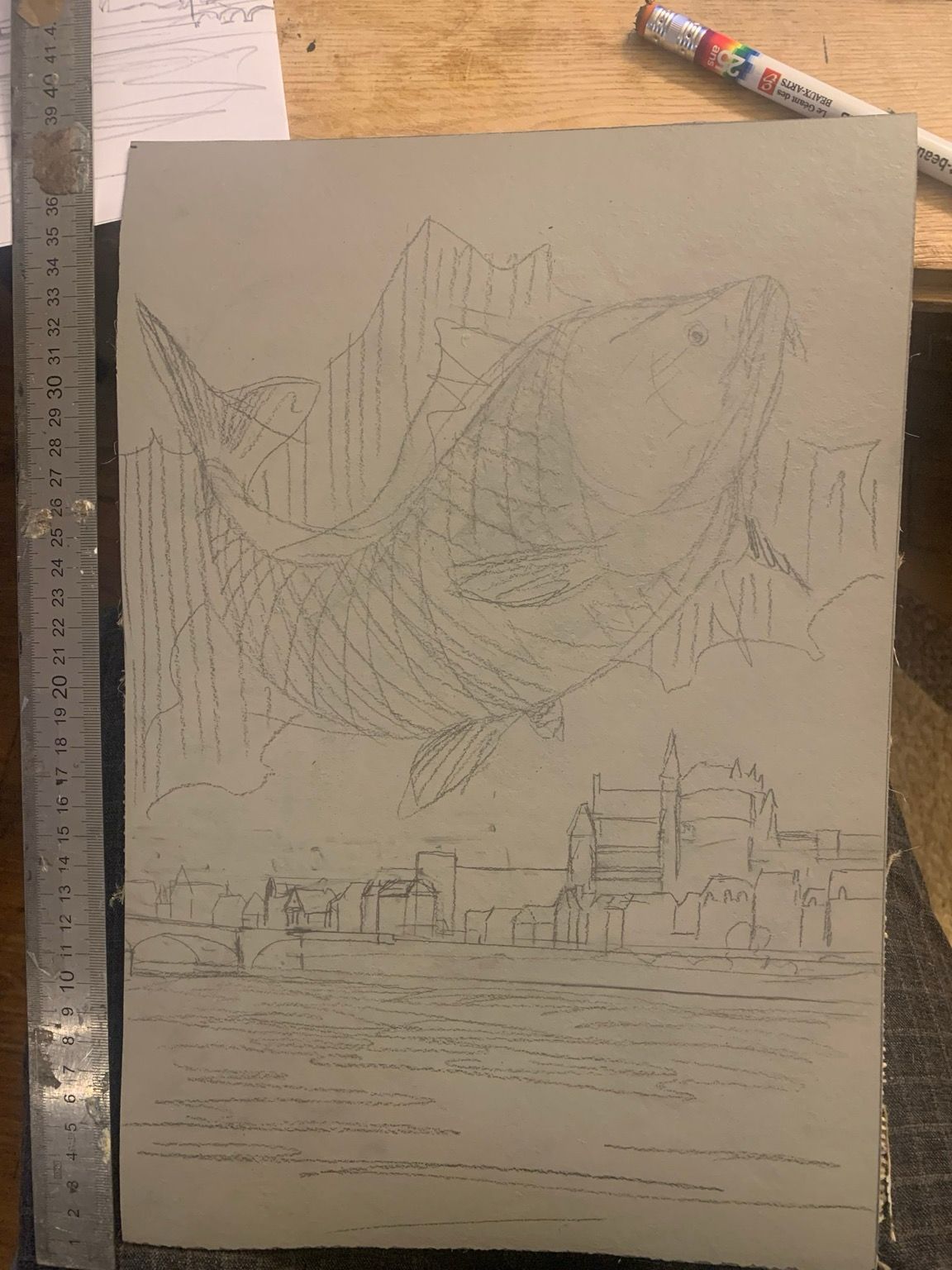 Croquis sur une plaque de Lino gris d’une grosse carpe avec une ville en bord de fleuve derrière