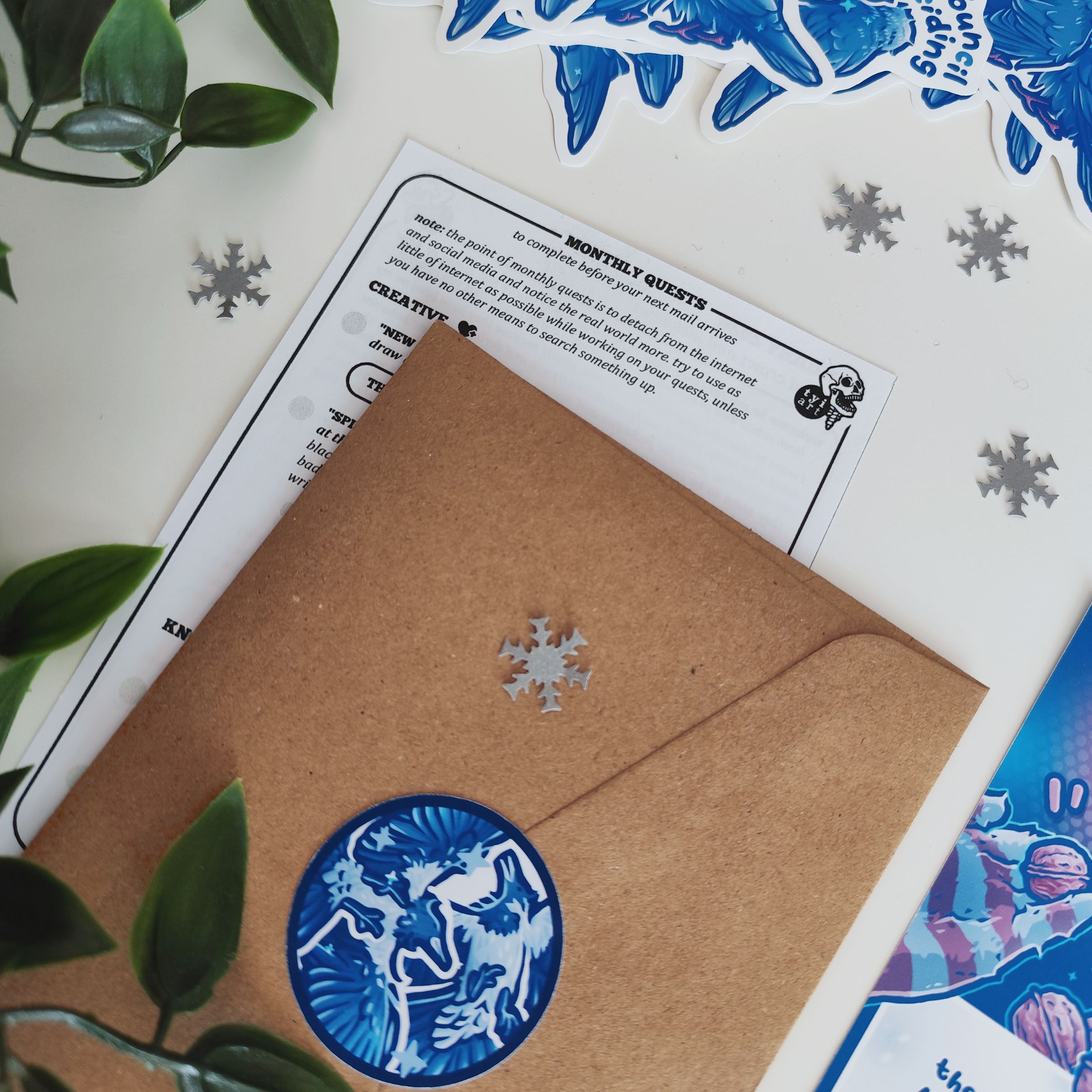 photo of my monthly mail brown envelope with a corvid sticker on it, and a letter with monthly quests behind it