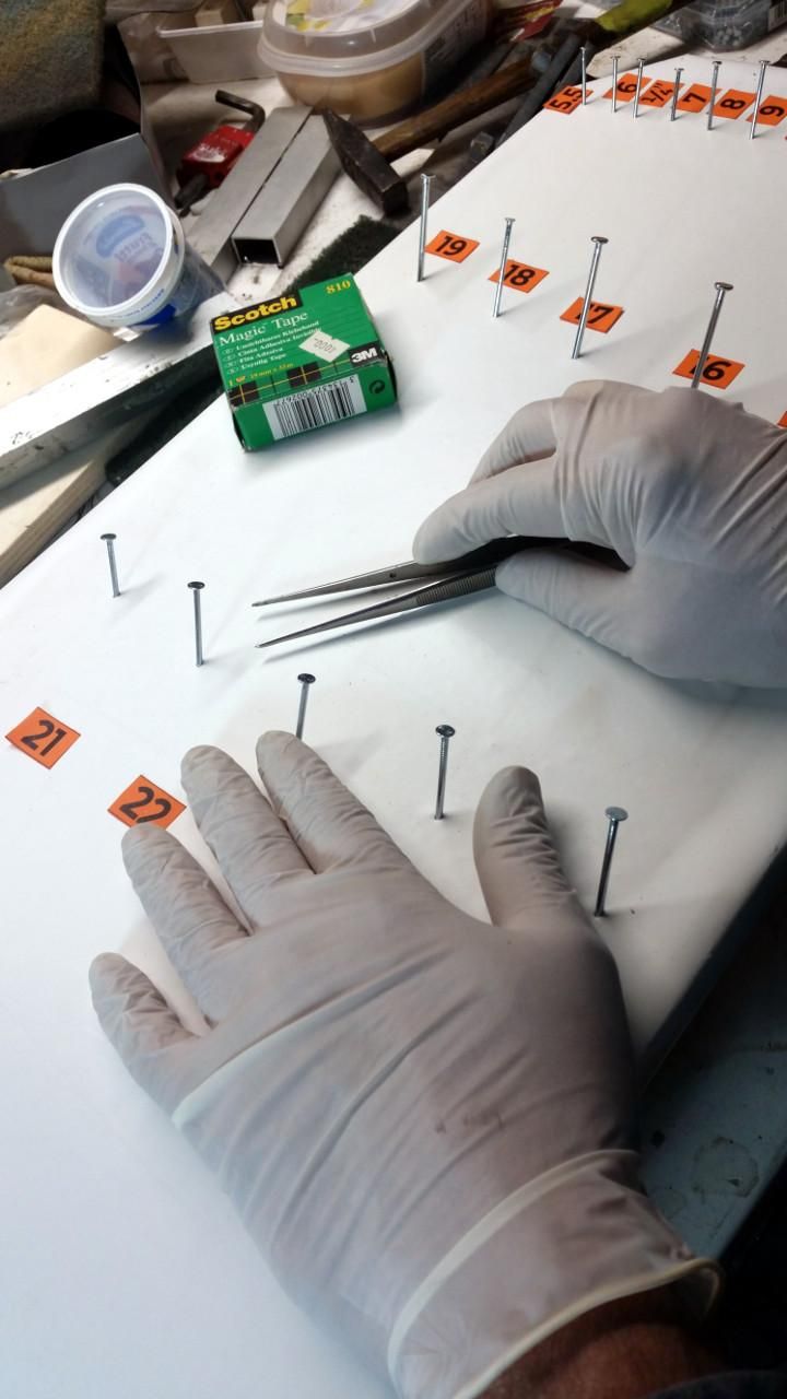 Due mani guantate sul pannello delle chiavi, con un paio di pinzette molto sottili.