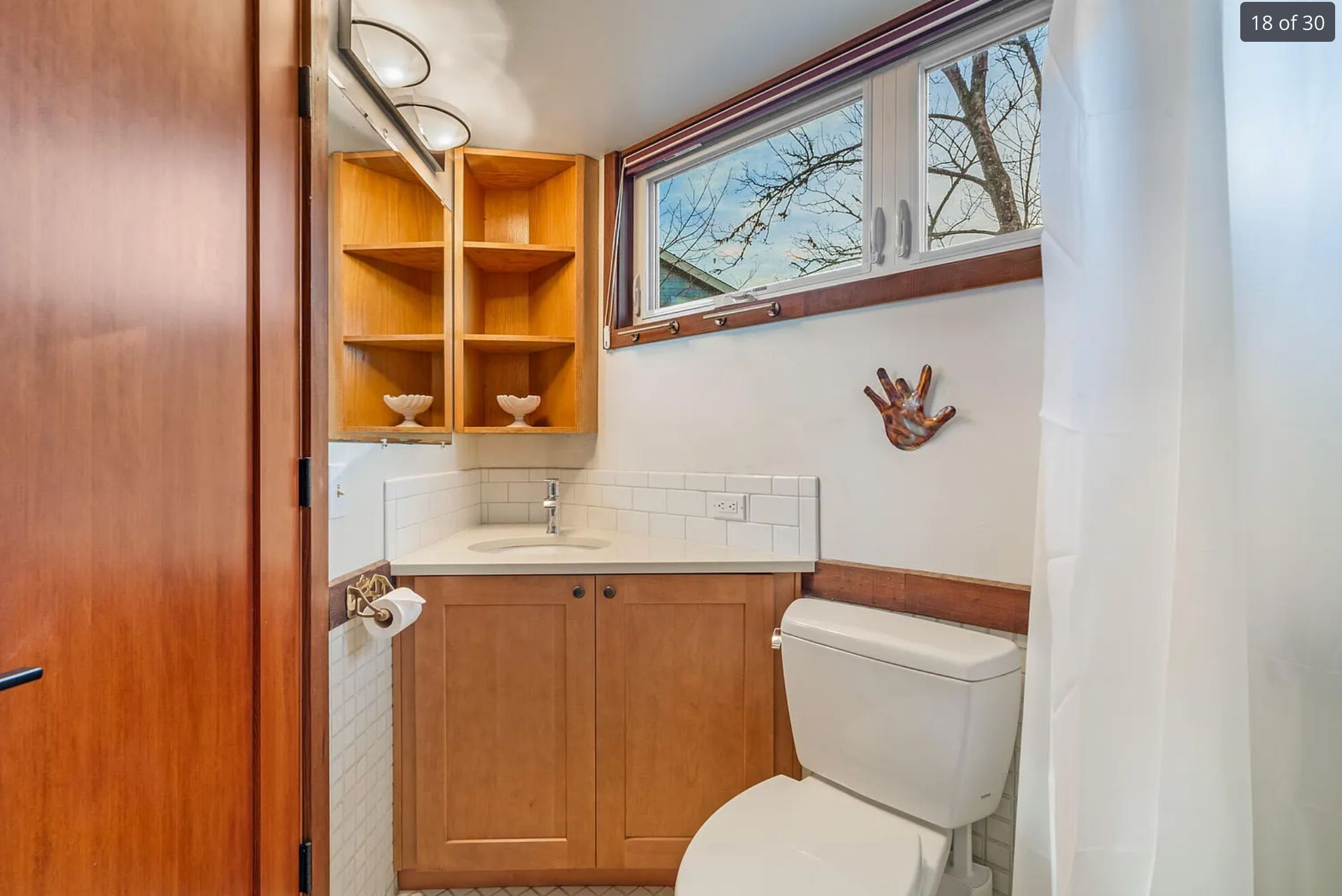A bathroom crammed into a corner space and it looks like the door would hit the toilet when you open it, and it looks impossible to get into the vanity because the toilet and toilet paper roll holder would be in the way. 