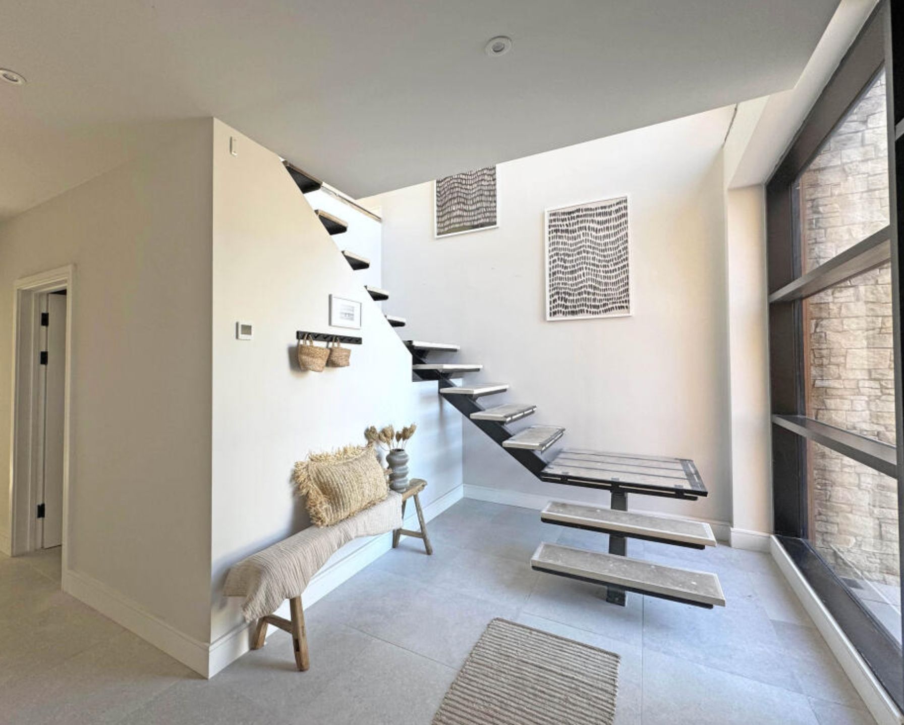 A modern looking home interior showing stairs with no railing that curve around and I am 100% certain I'd fall off. 
