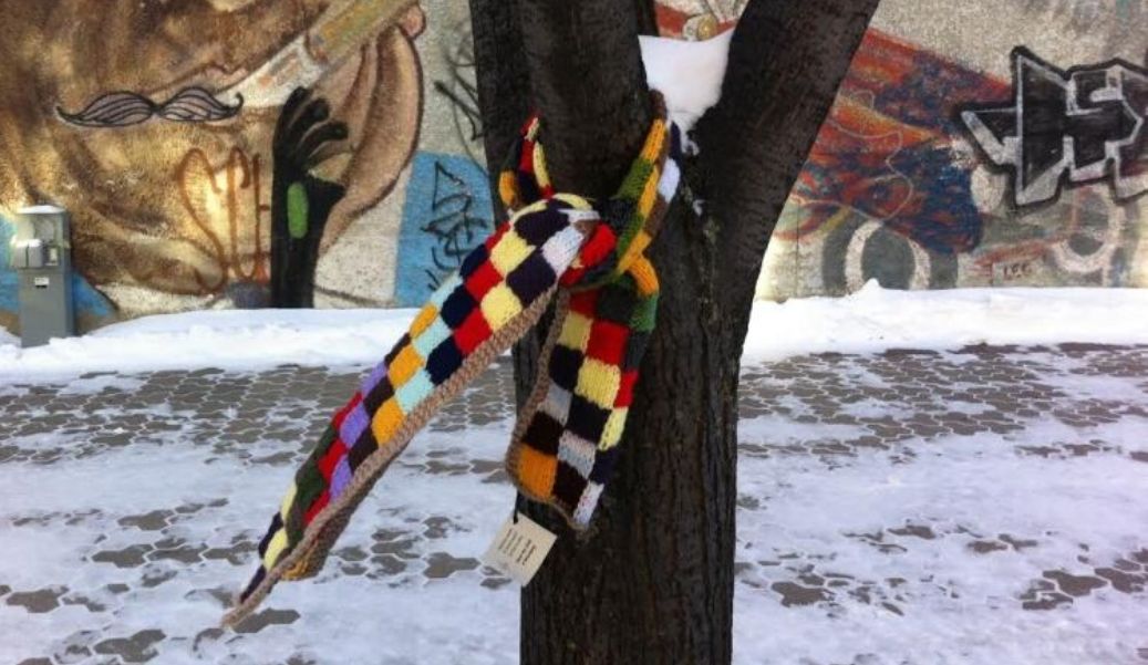 A free multicolored scarf is shown on a tree. The picture is from Winnipeg where people were sharing them. Pic via CBC.