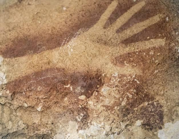 Hand painting similar to the first photo made by putting your hand on a cave wall and spraying it with pigment from a straw. This paint looks like a dark ochre. The hand and arm are long and slender. This one is from a cave in Borneo and was dated to approx 40,000 years ago 