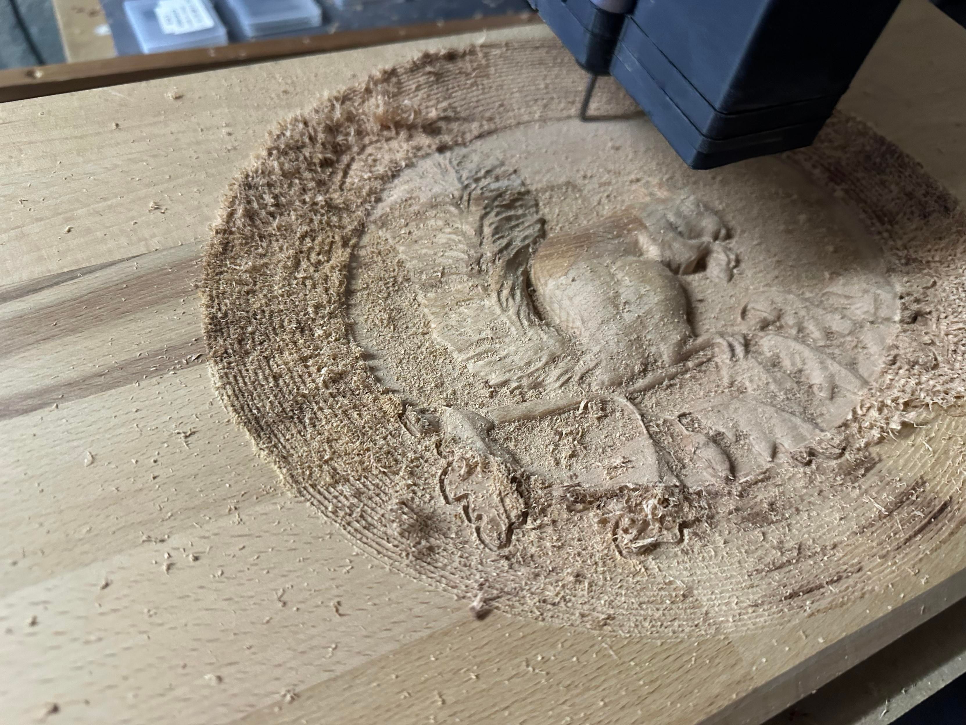 block of oak countertop on a CNC machine that has a squirrel in a dish cut out in the process of doing a finishing path that started from the middle so the center is nicely smooth and detailed while the outer third is all rough and terraced