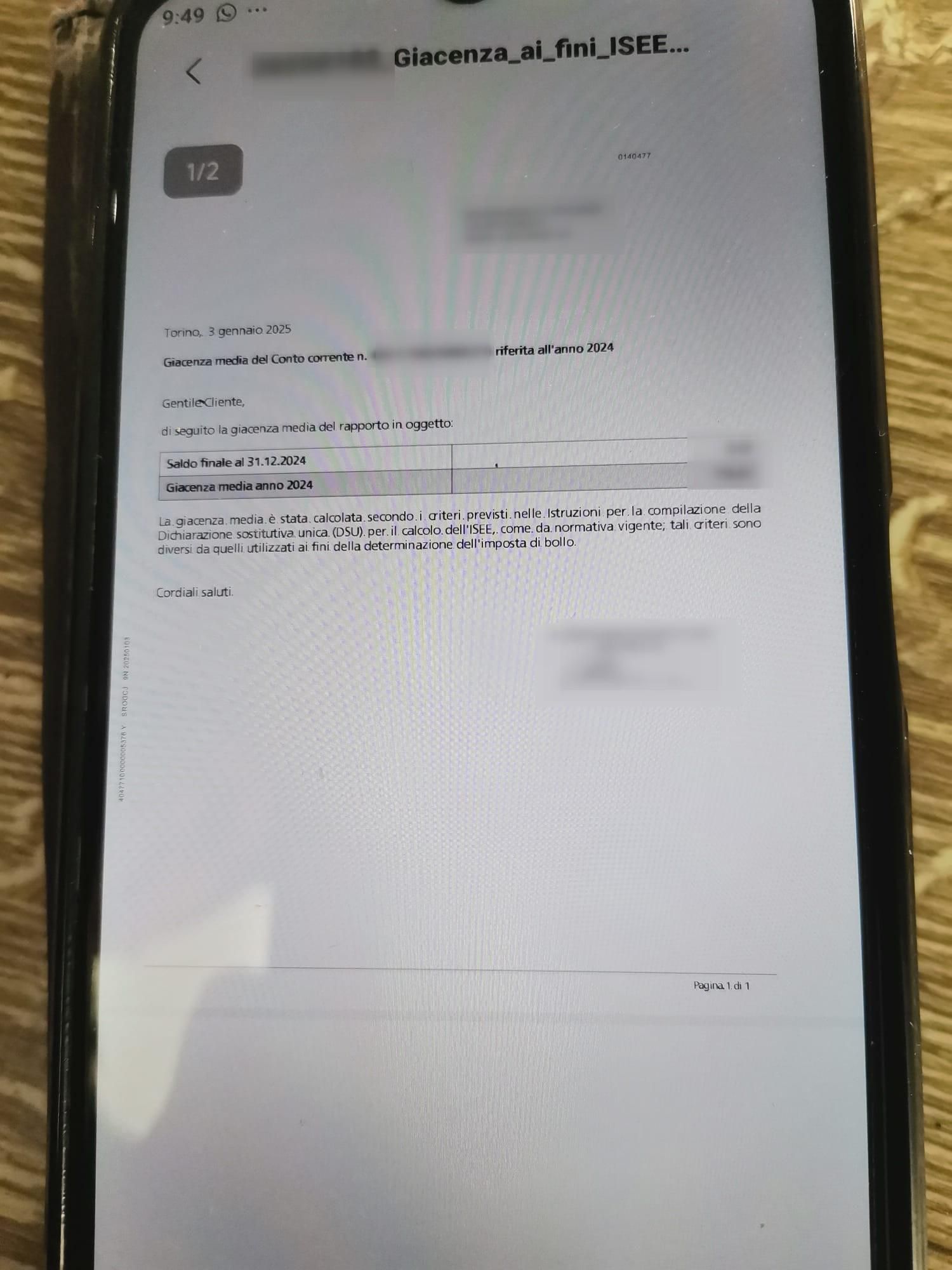 foto di uno smartphone poggiato su un piano di legno, sullo schermo un documento ISEE con del testo e alcune parti offuscate