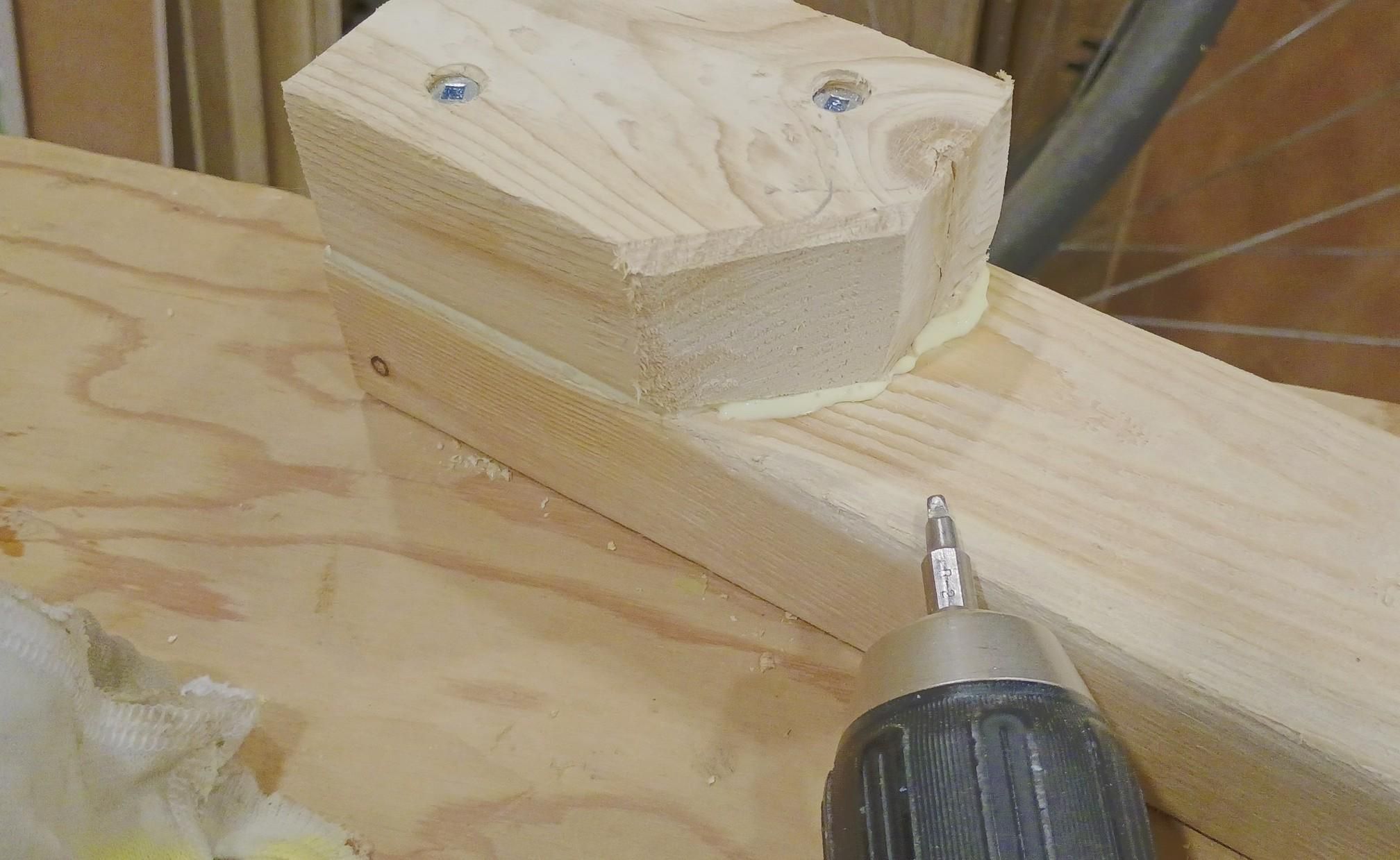 A block of wood is attached to another length of wood with glue and couple of screws. The glue application appears successful because there's some being squeezed out of the joint as it's tightened. 

It gets wiped away with a damp rag before it starts to set leaving a clean tight joint.