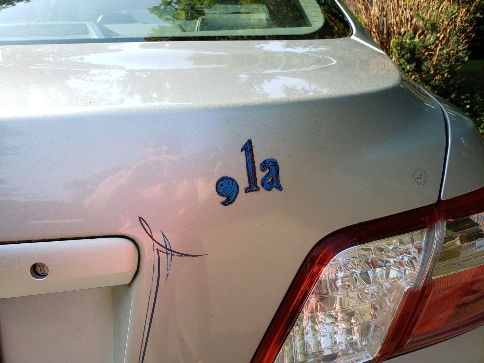 A close-up of magnets on a car: comma, lowercase l, lowercase a.