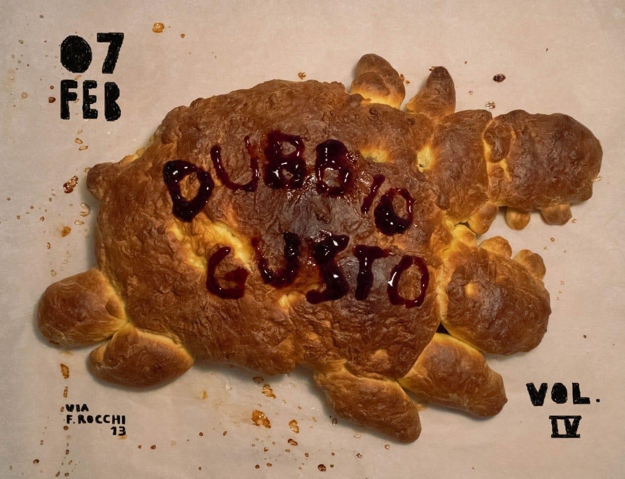 Volantino della serata "Dubbio Gusto in Spazio Angusto Vol IV". Al centro un prodotto di panificazione informe, con la scritta "Dubbio Gusto" realizzata con una marmellata rossa