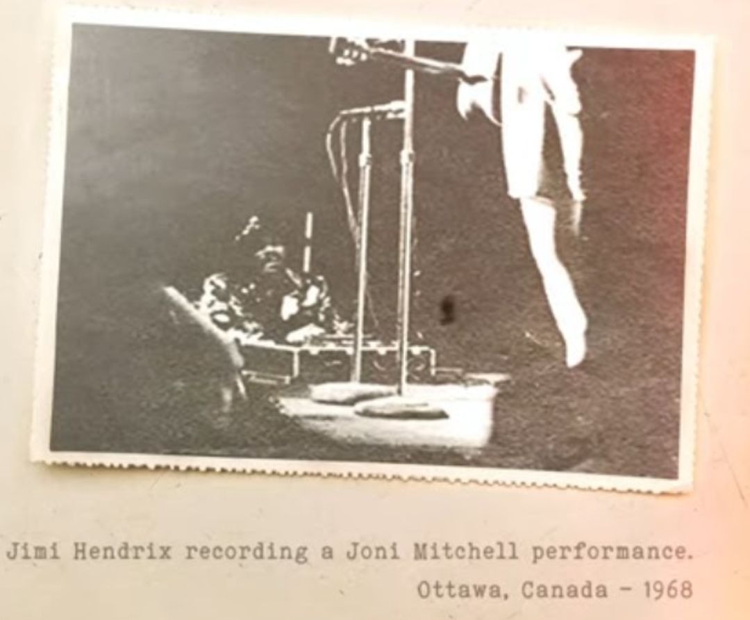 A dark image shows Jimi Hendrix sitting at the foot of a stage with recording gear, capturing Joni Mitchell singing