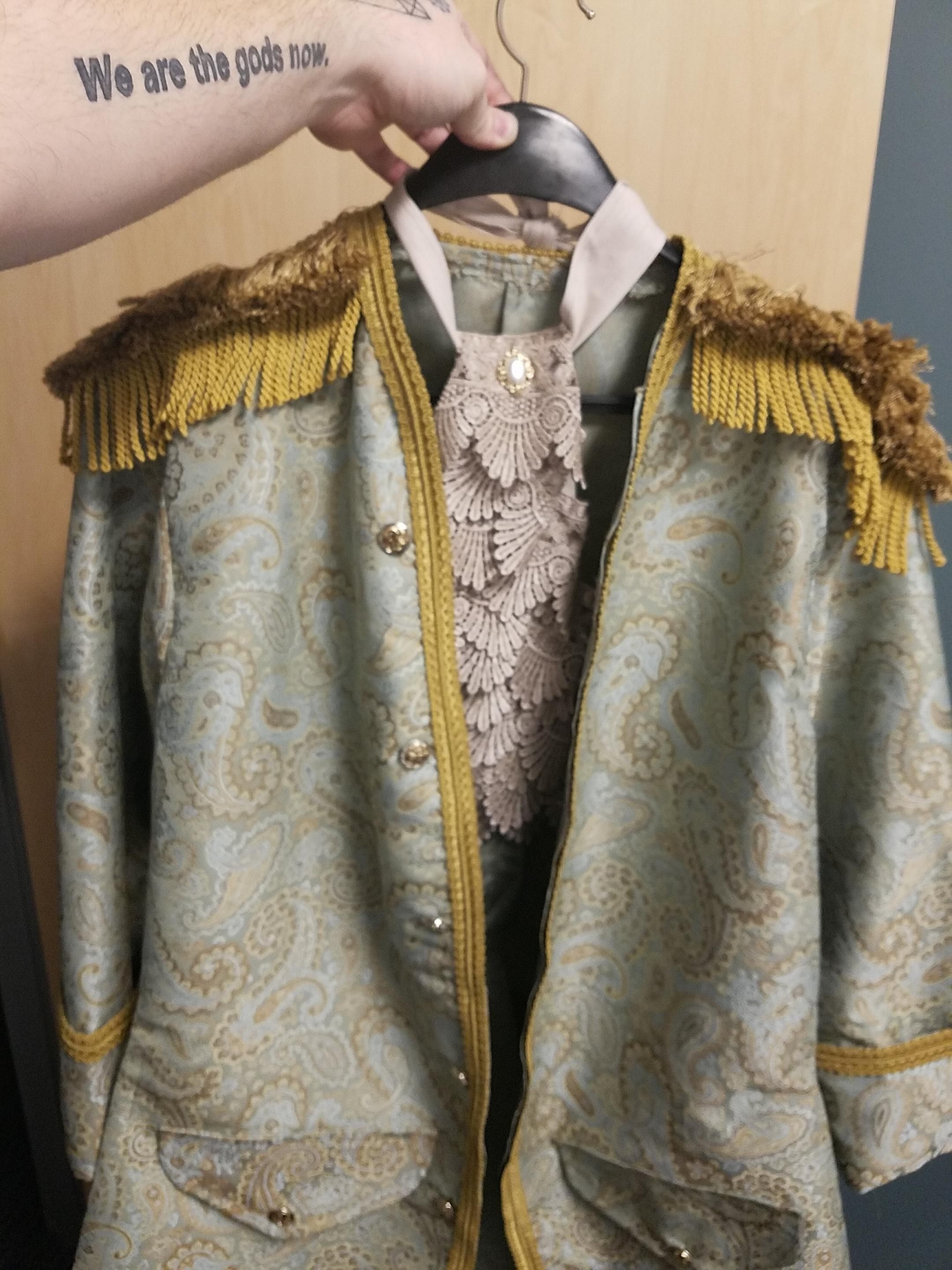 A pale blue paisley and gold rococo style jacket with gold epaulettes and a dusty grey lace jabot