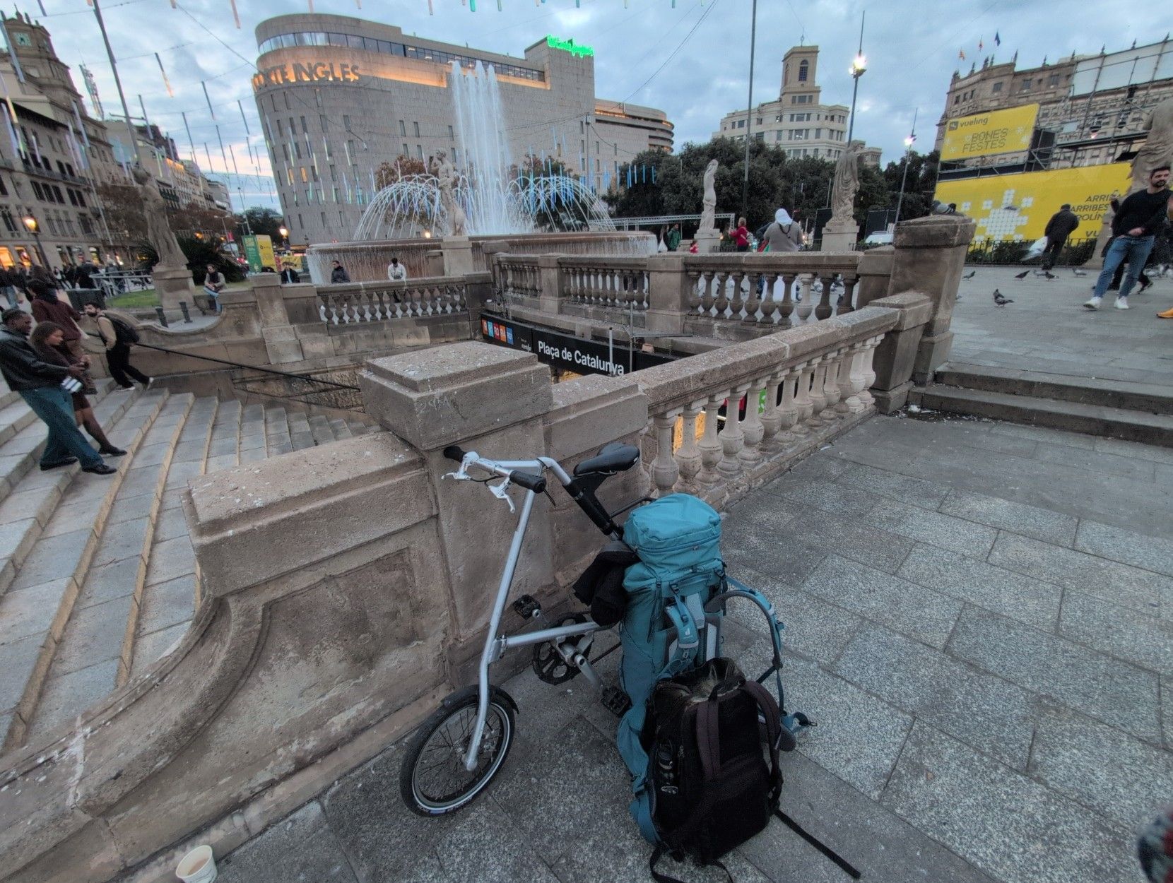 Wide-angle picture of my foldable bike and my two backpacks in front of the Plaça de Catalunya subway stop.