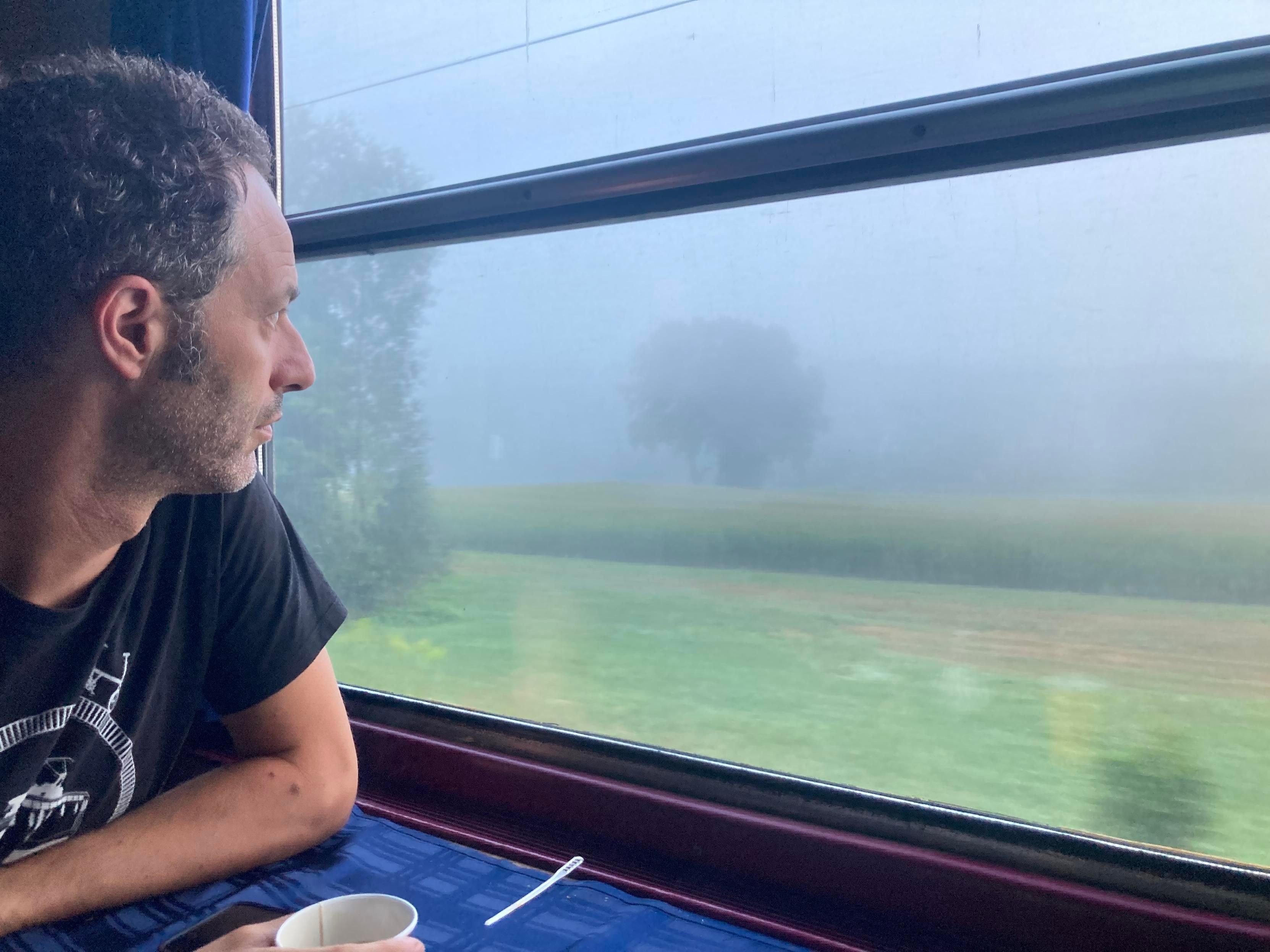 Jon staring out of the window onto a foggy landscape from the dining car on Optima Express