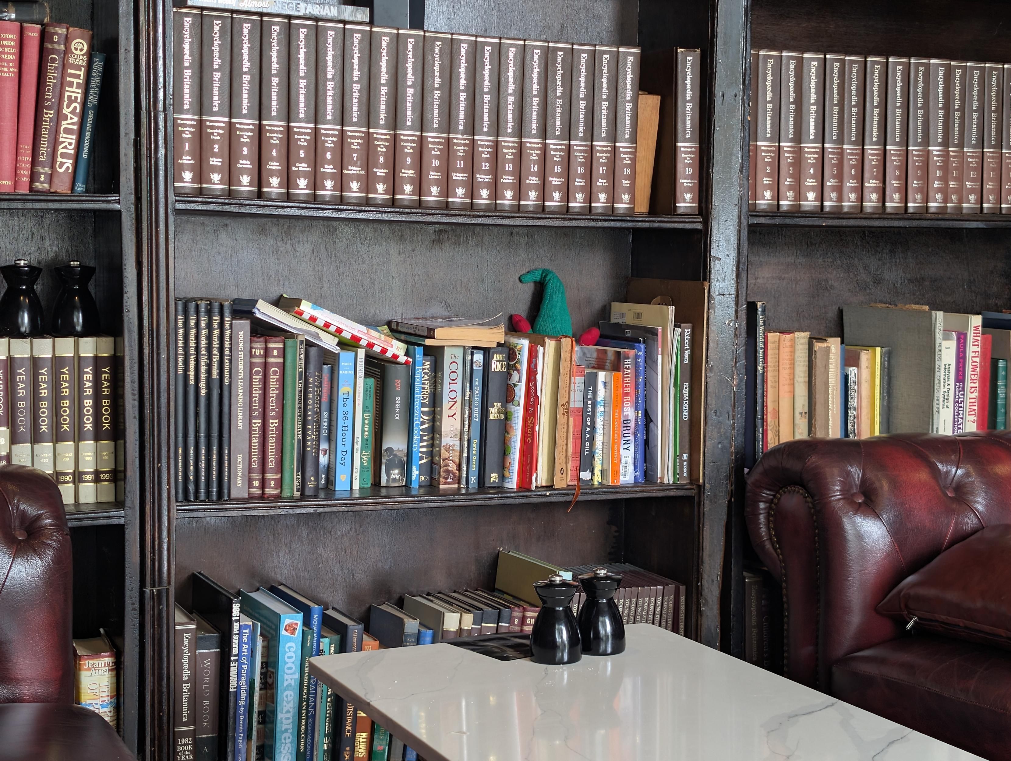 A bookcase with a little green hat and red hands showing