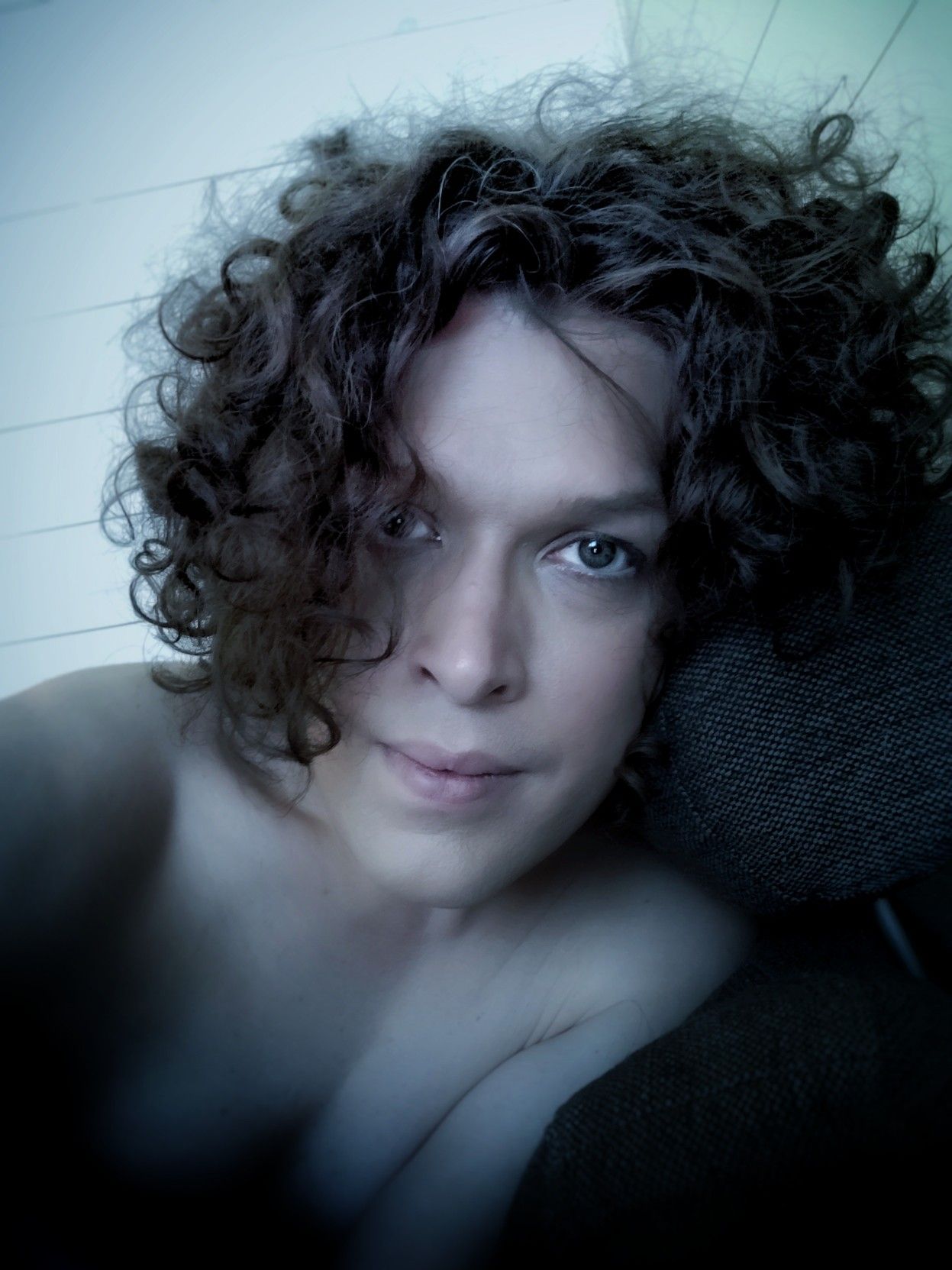 I'm leaning to the side against the back of the sofa I'm looking into your eyes. I'm not wearing a shirt but with the shadows nothing in particular is revealed.