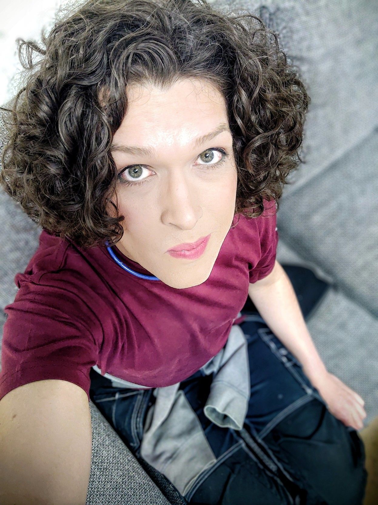 another millennial selfie, of me in a burgundy t-shirt and work pants, sitting in a sofa