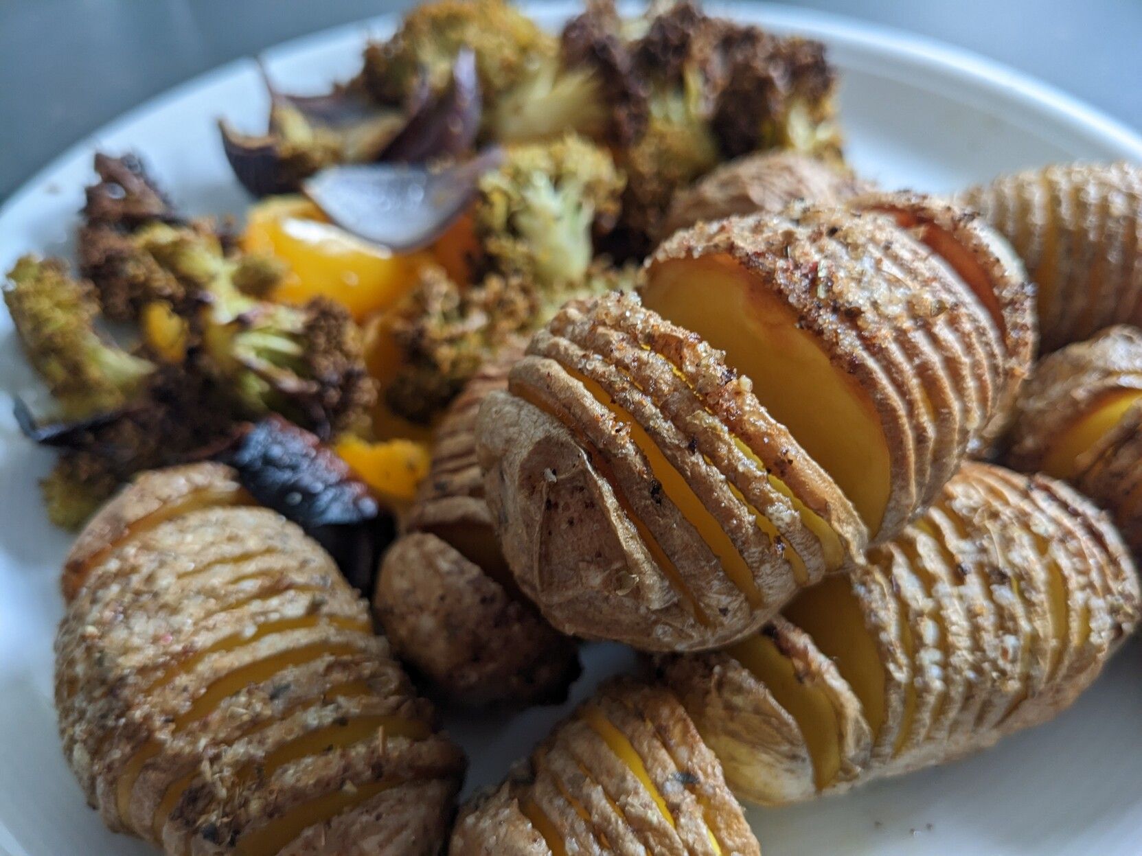 Potatoes with a lot of parallel cuts, roasted, with vegetables.